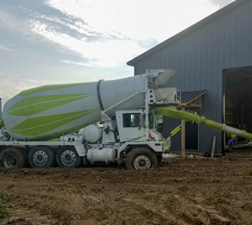 A cement truck pouring concrete near a sand pile.