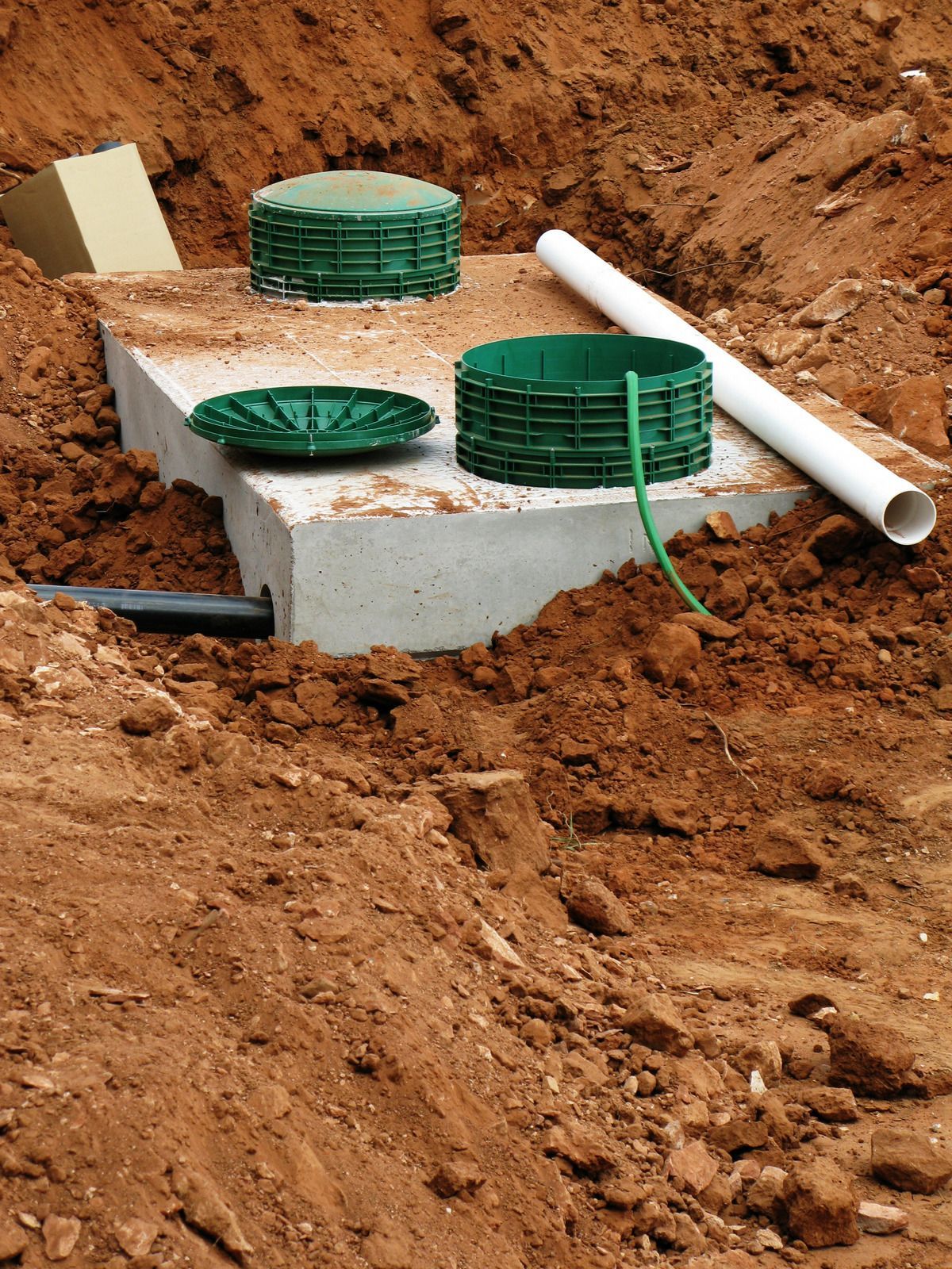 Plastic utility boxes and pipes on a concrete slab in a dirt excavation site