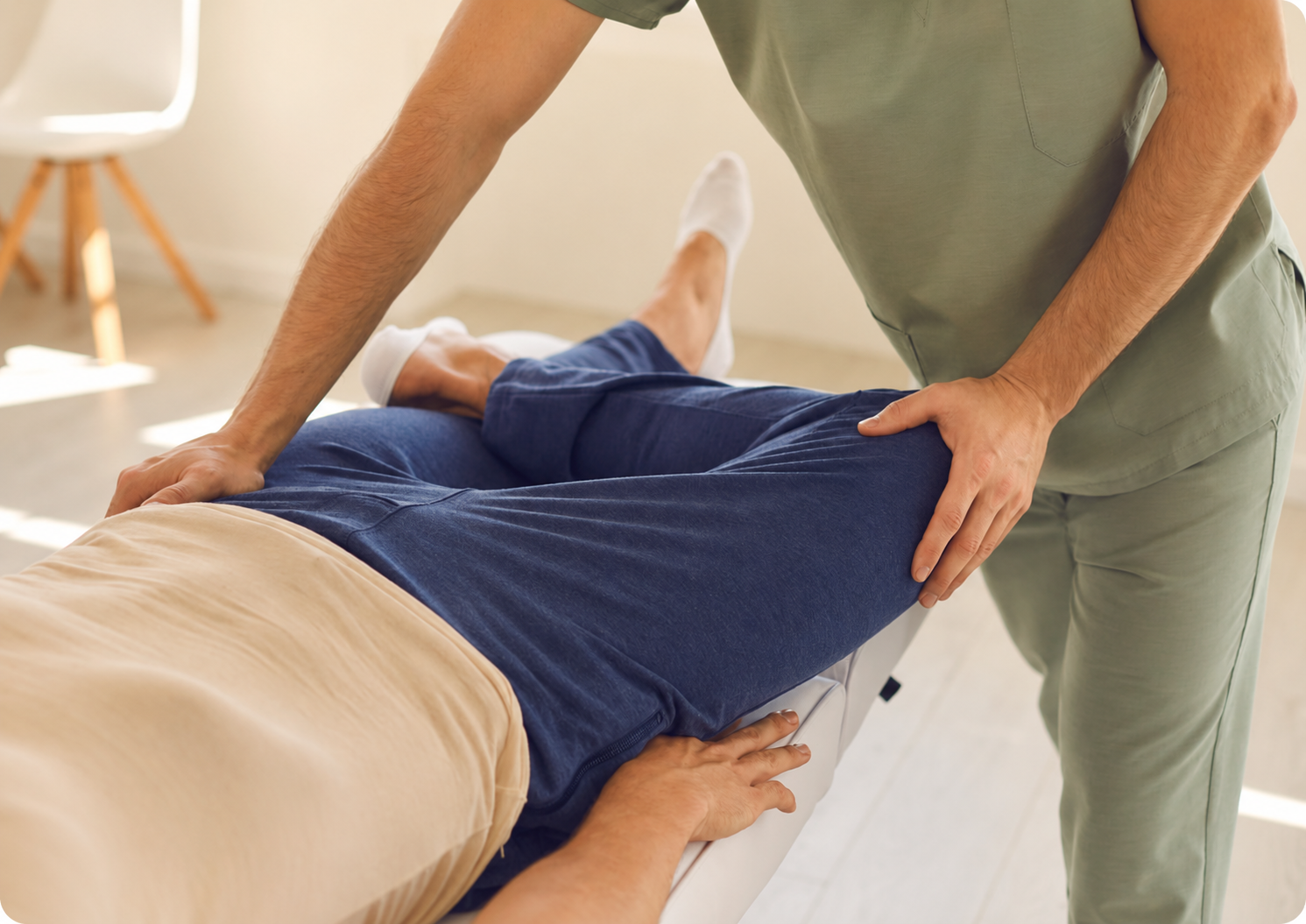 Uma mulher de jaleco branco realiza uma massagem nas costas de uma cliente sentada, utilizando uma bola de exercícios rosa