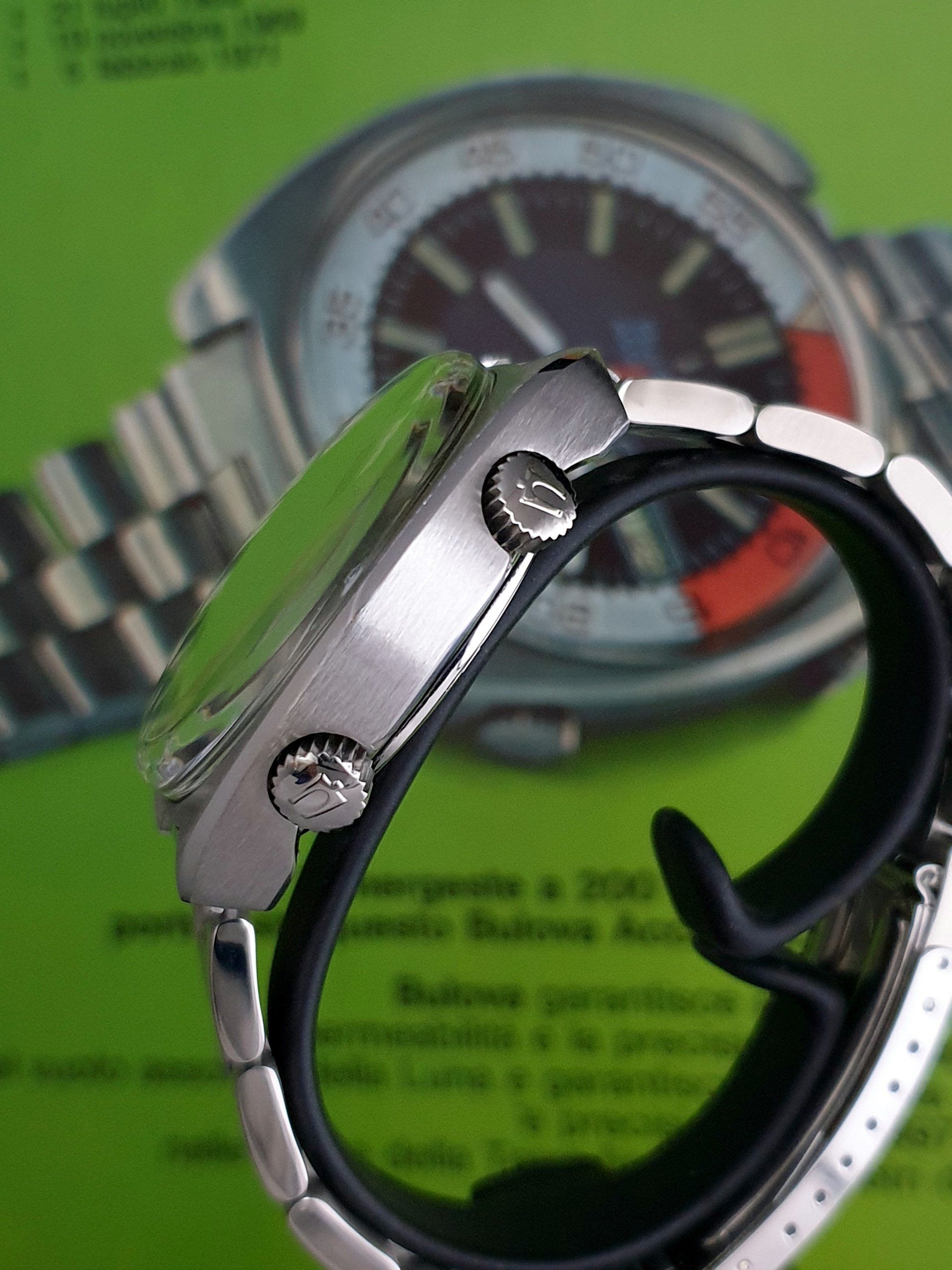 Close-up of a silver wristwatch with a black band on a green background