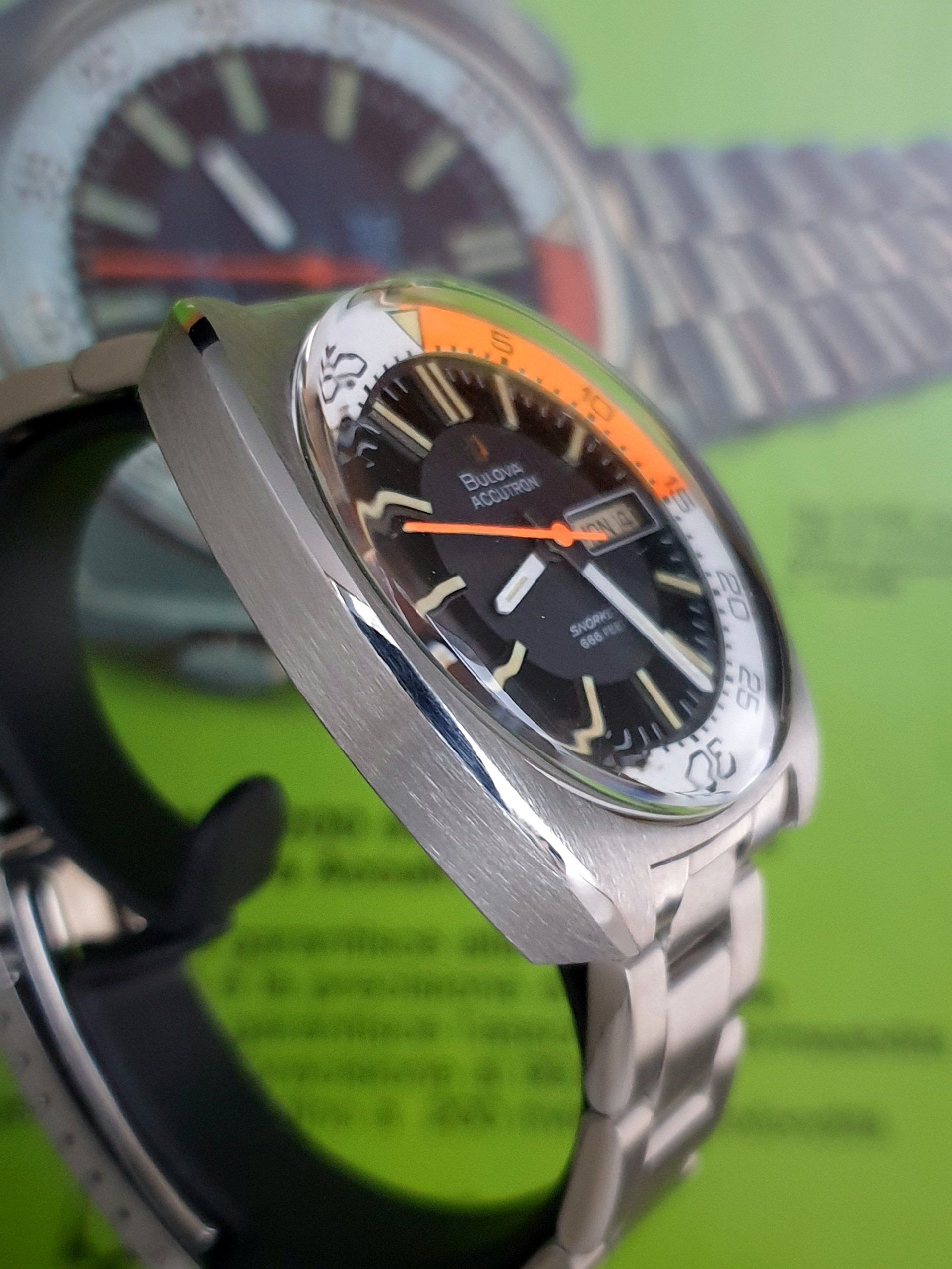 Close-up of a silver wristwatch with a black dial and orange accents on a display stand