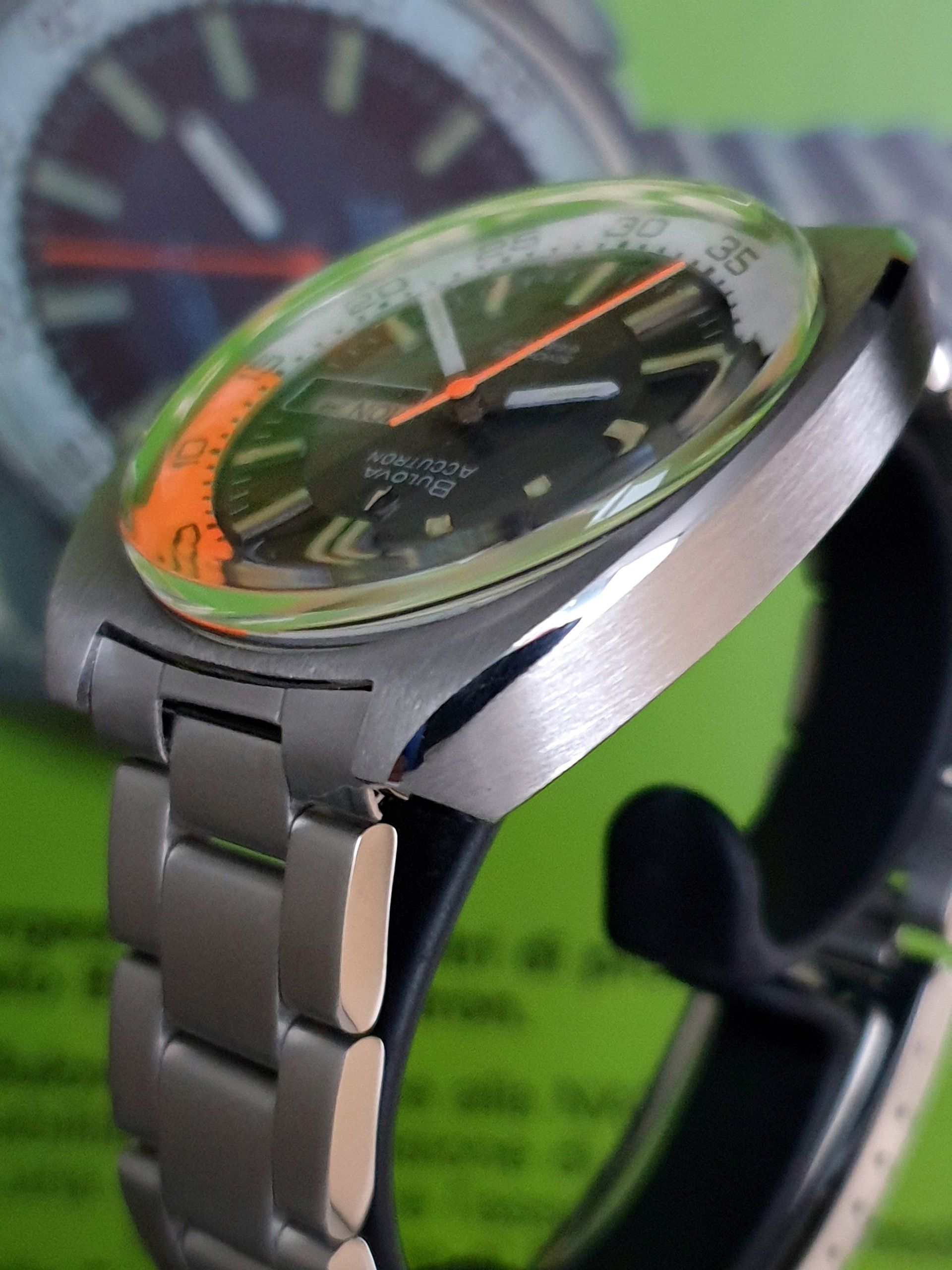 Silver wristwatch with orange accents on a black stand, close-up against a blurred background