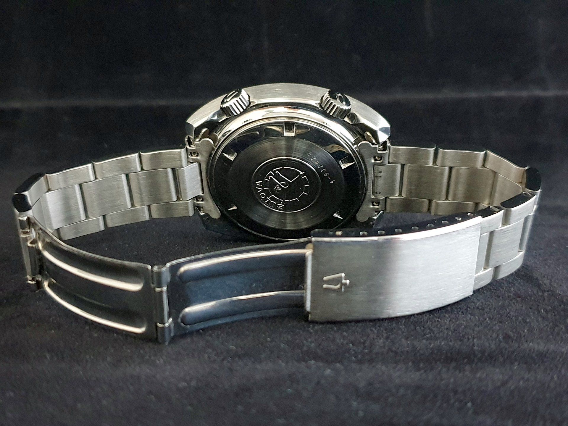 Silver wristwatch with metal band, shown from the back on a black cloth surface