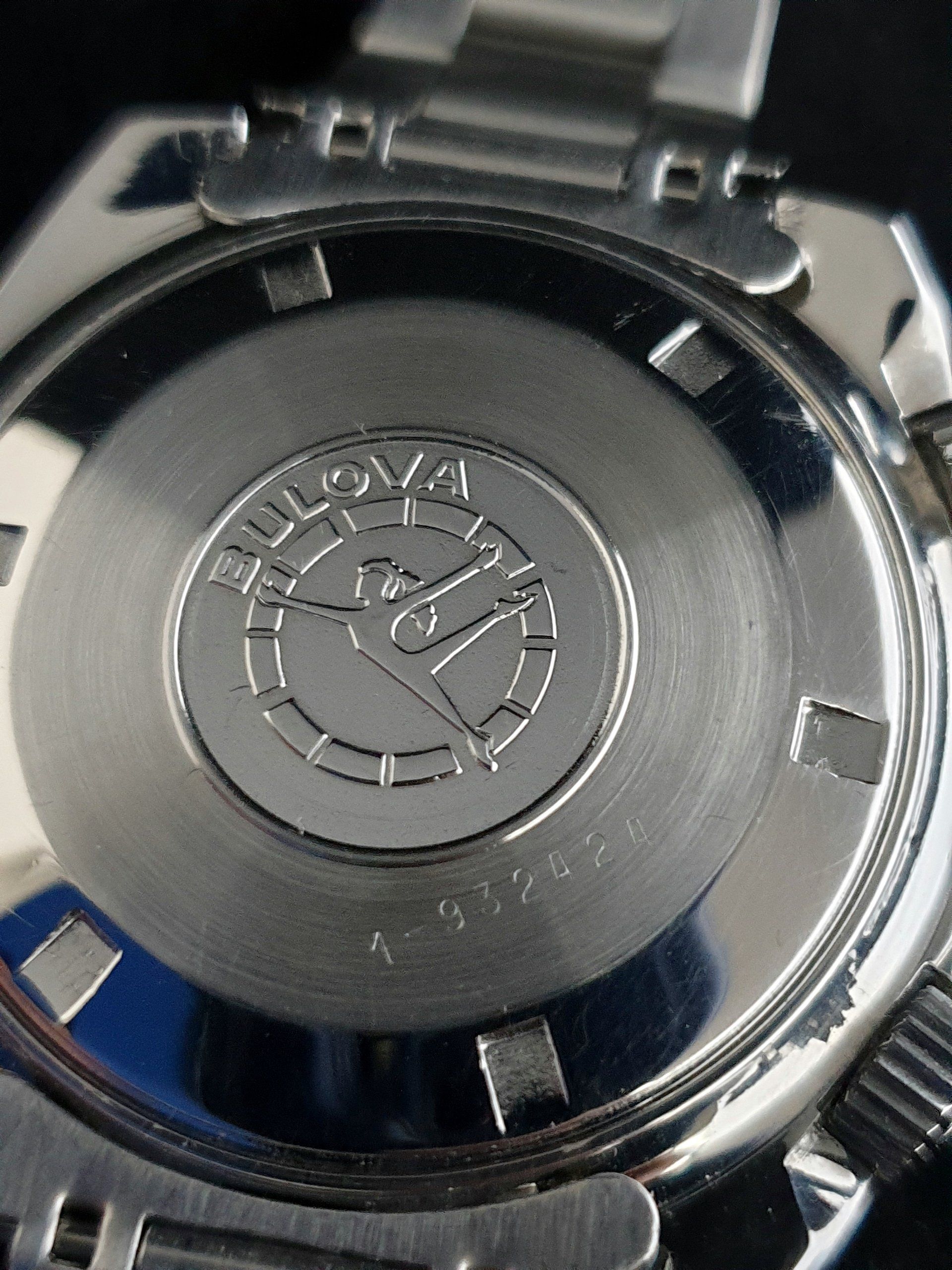 Close-up of a silver Bulgari watch case back with engraved logo and metal bracelet