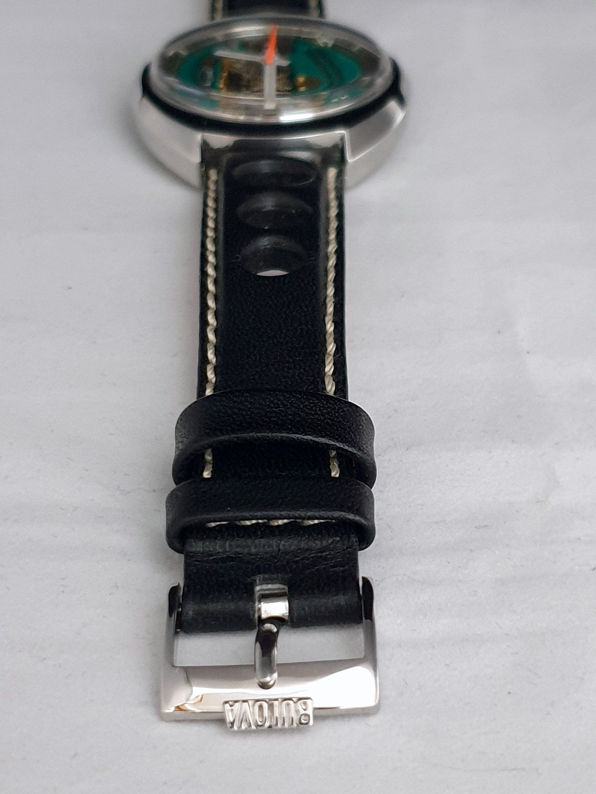 Black leather wristwatch with a silver case and buckle, viewed from above on a white background