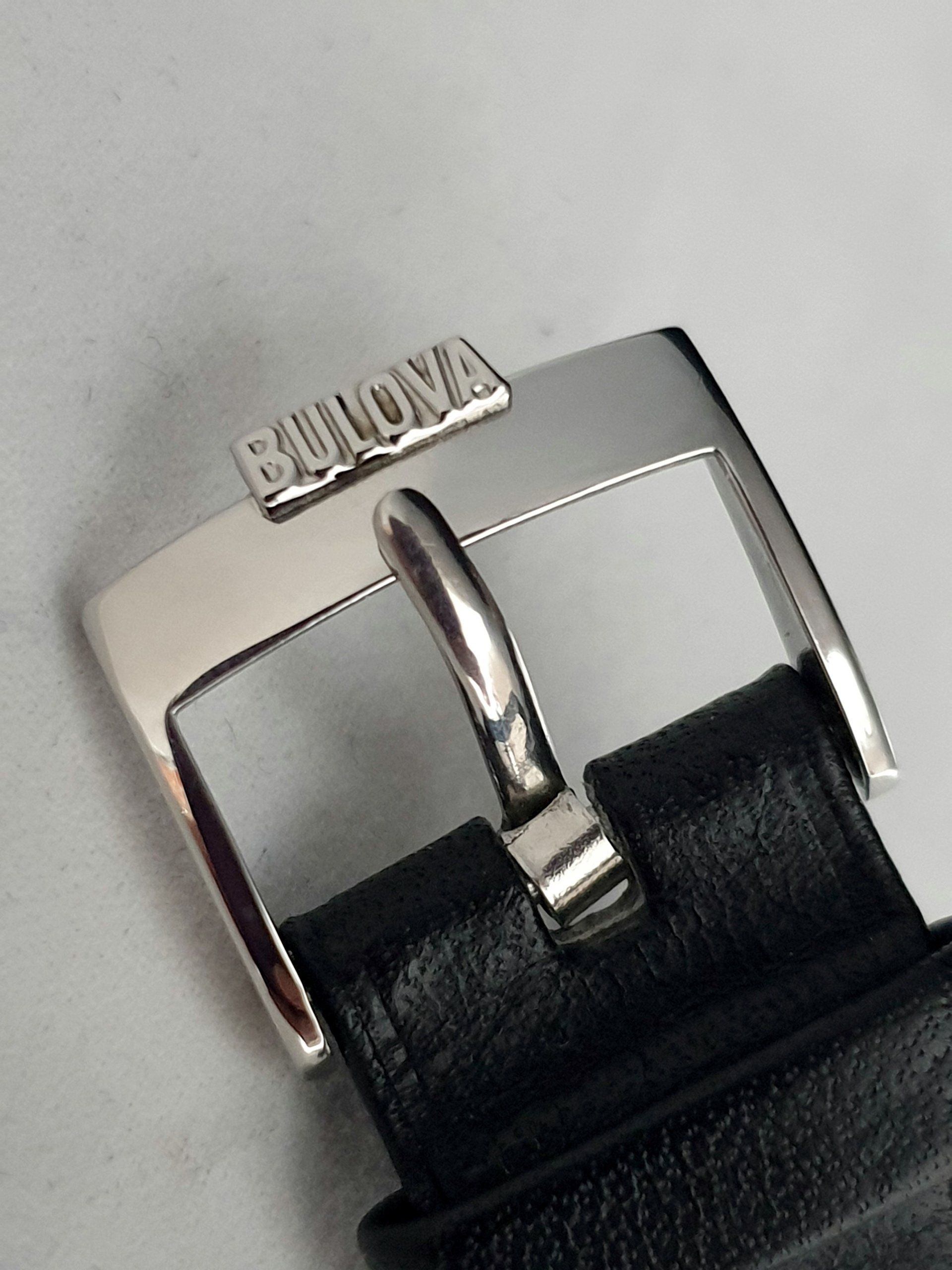 Close-up of a silver Bulova watch clasp on a black leather strap