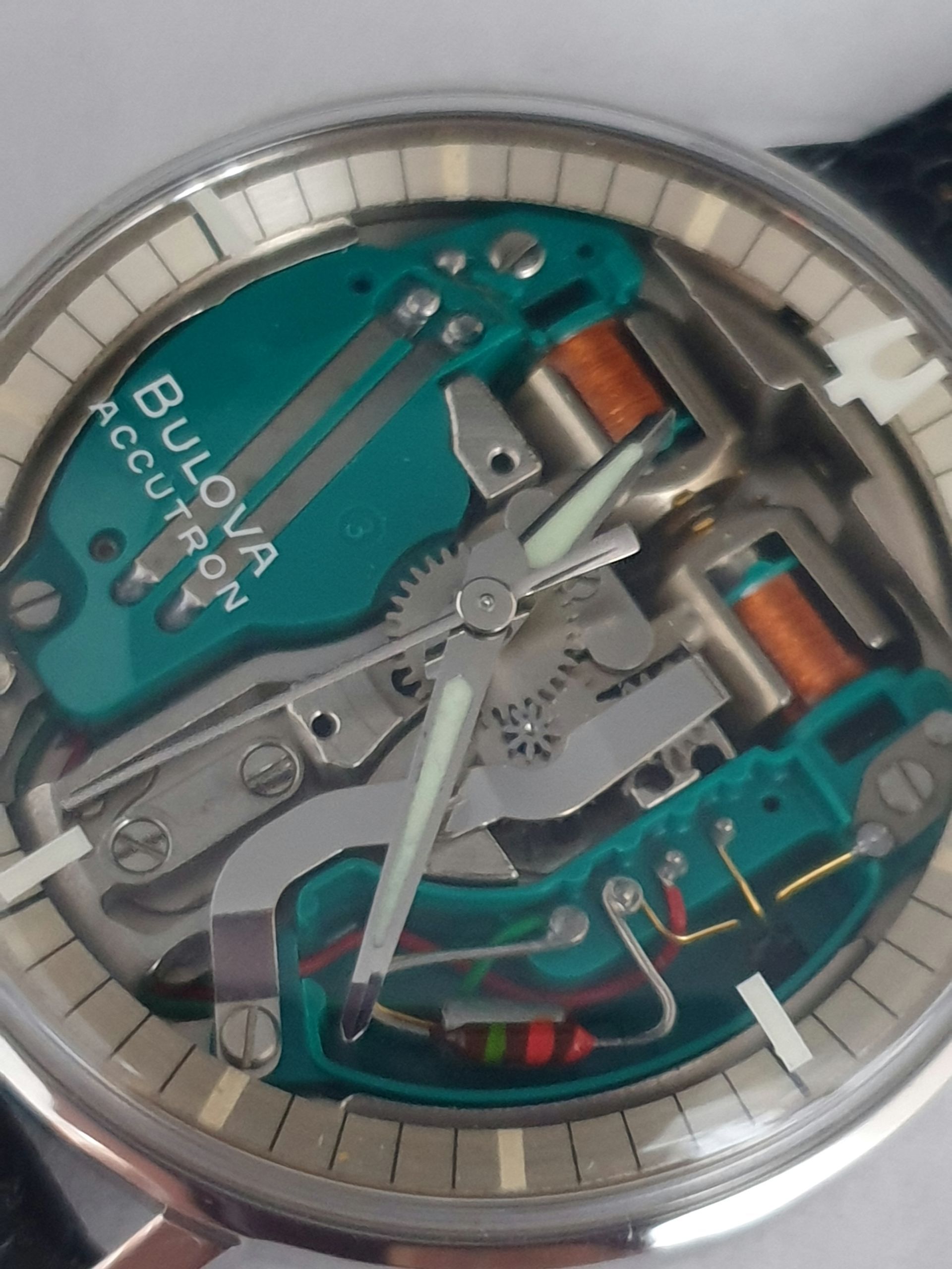Close-up of a Bulova watch’s transparent mechanical movement with teal plates and copper coils