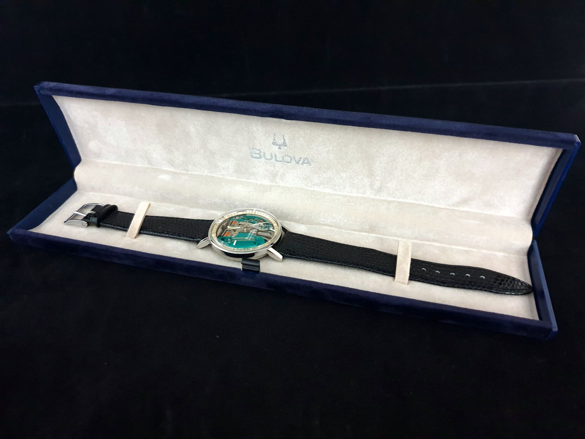 Bulova wristwatch in an open blue presentation case on a black background