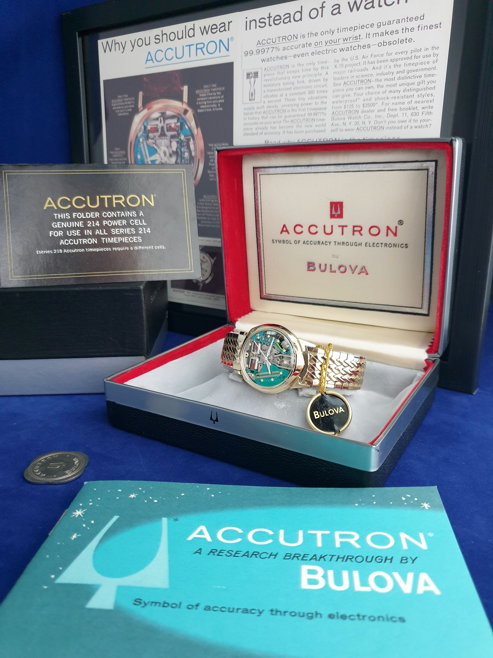 Accutron Bulova wristwatch set with red display box and promotional signs on a blue table.