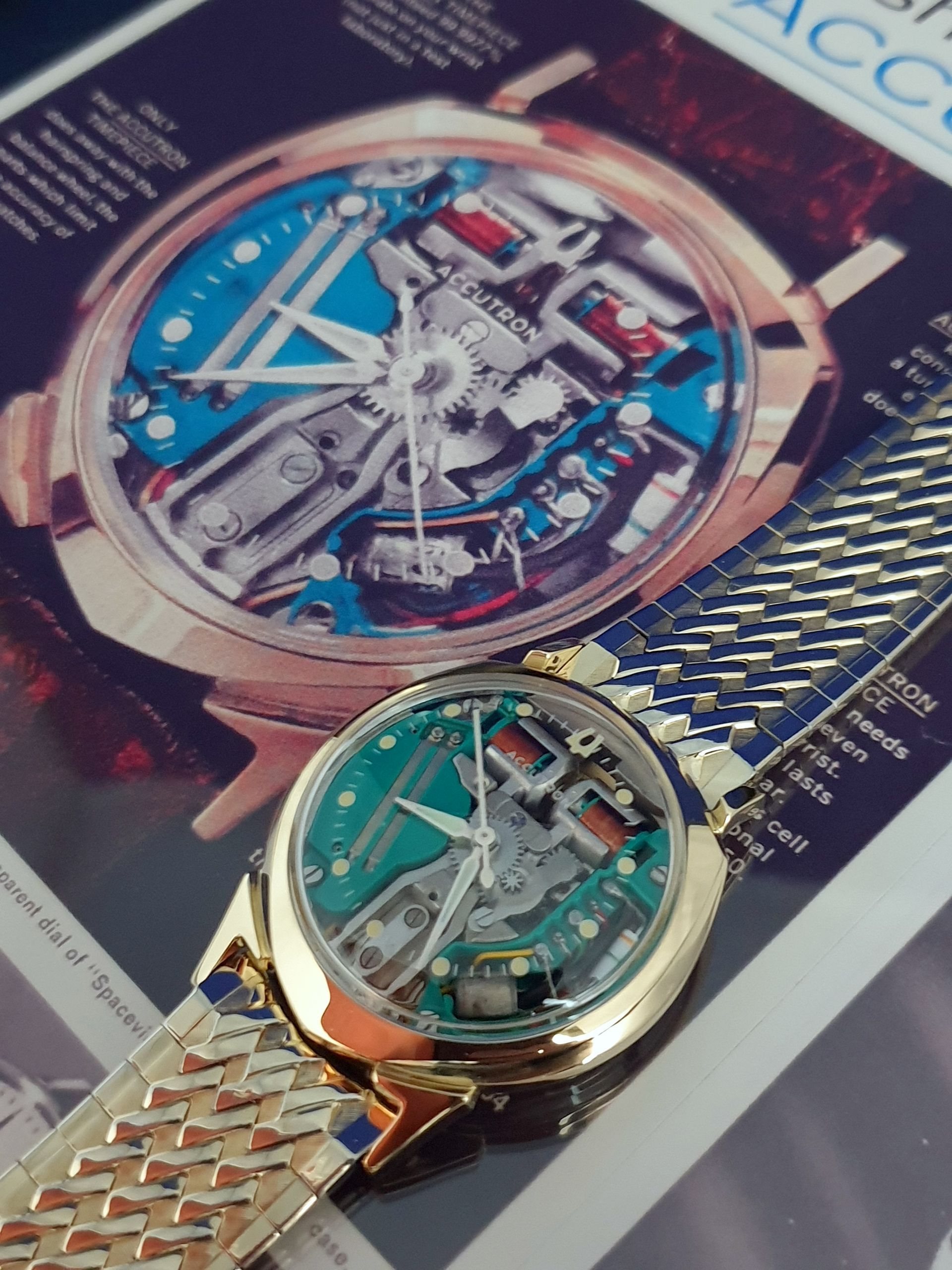 Two skeleton wristwatches with gold and silver mesh bands on a glossy magazine page