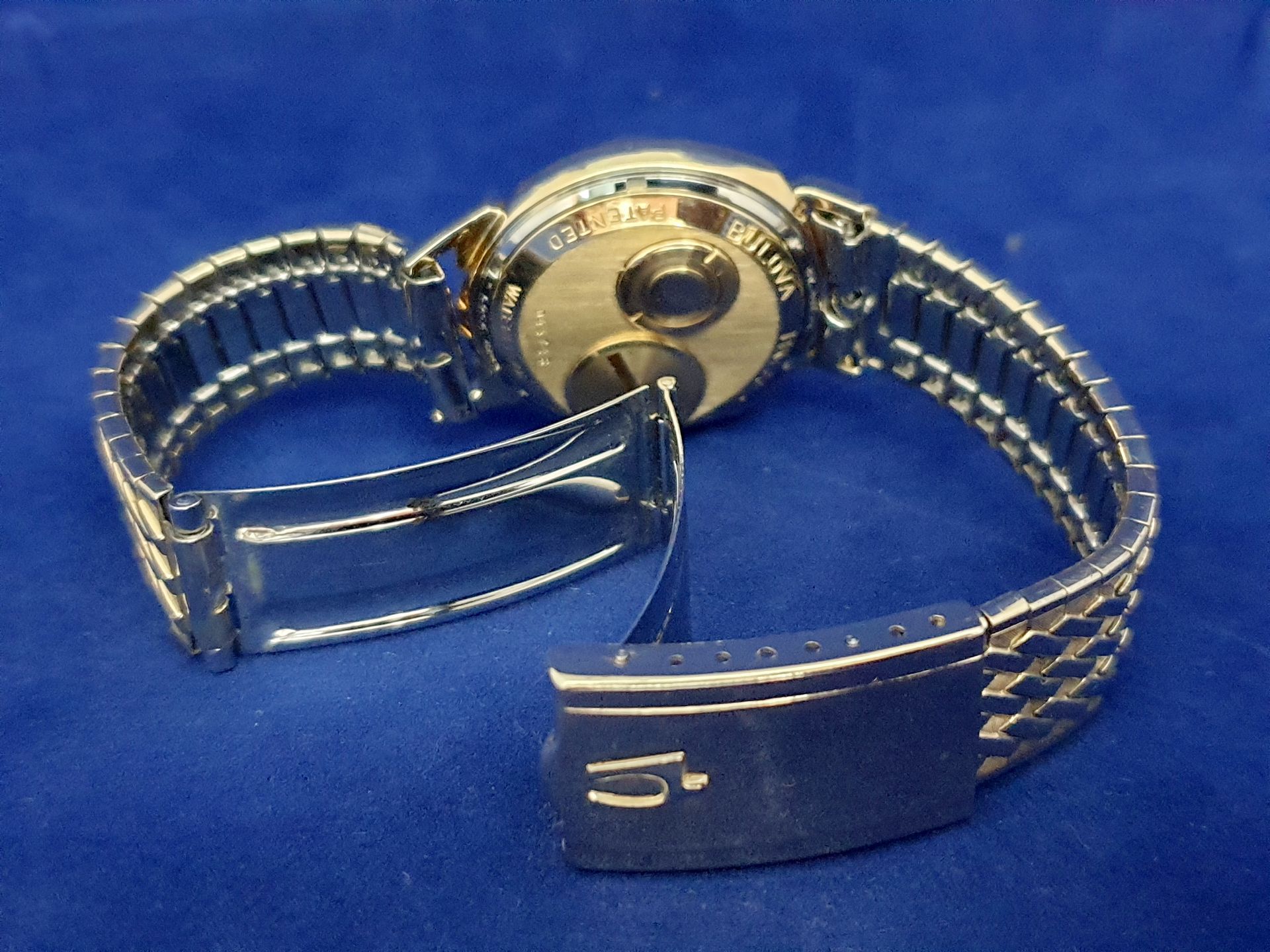 Silver wristwatch with open metal band on a blue background