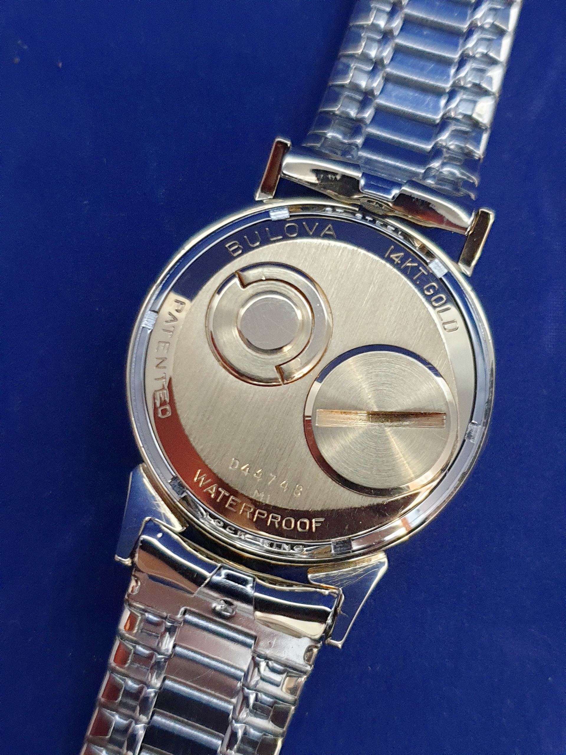 Back of a silver wristwatch on a blue background