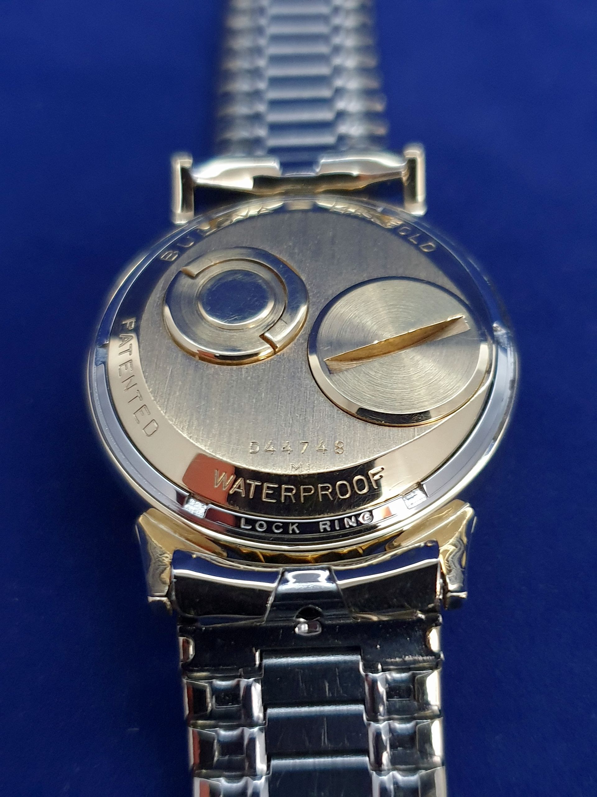 Close-up of a silver wristwatch with a black band on a blue background