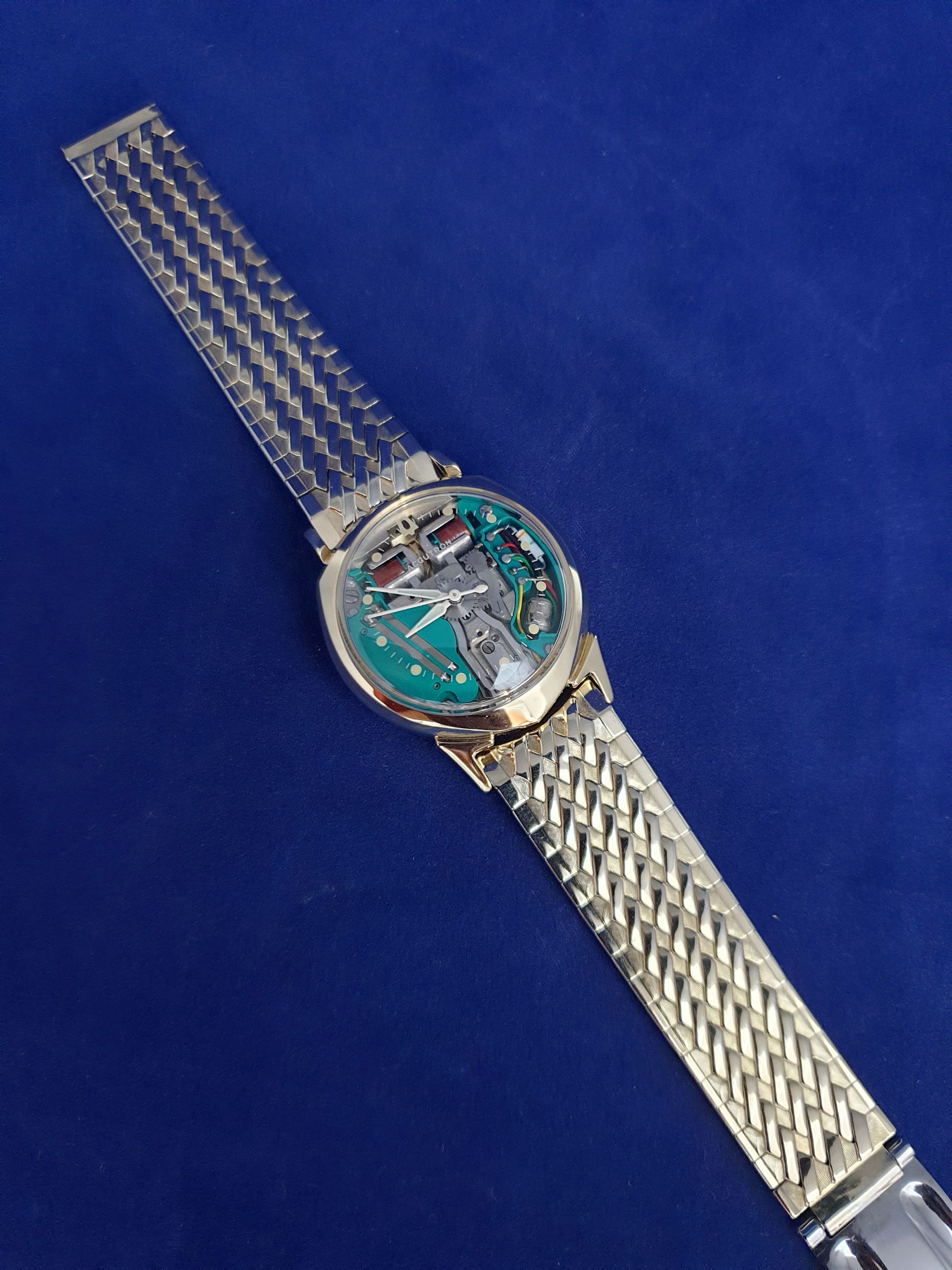 Silver wristwatch with turquoise face on a blue background