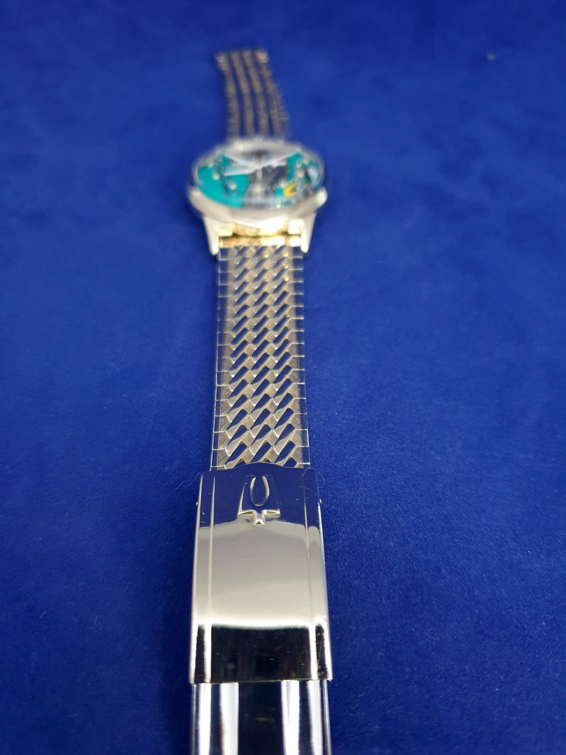 Silver wristwatch with a turquoise face on a blue background