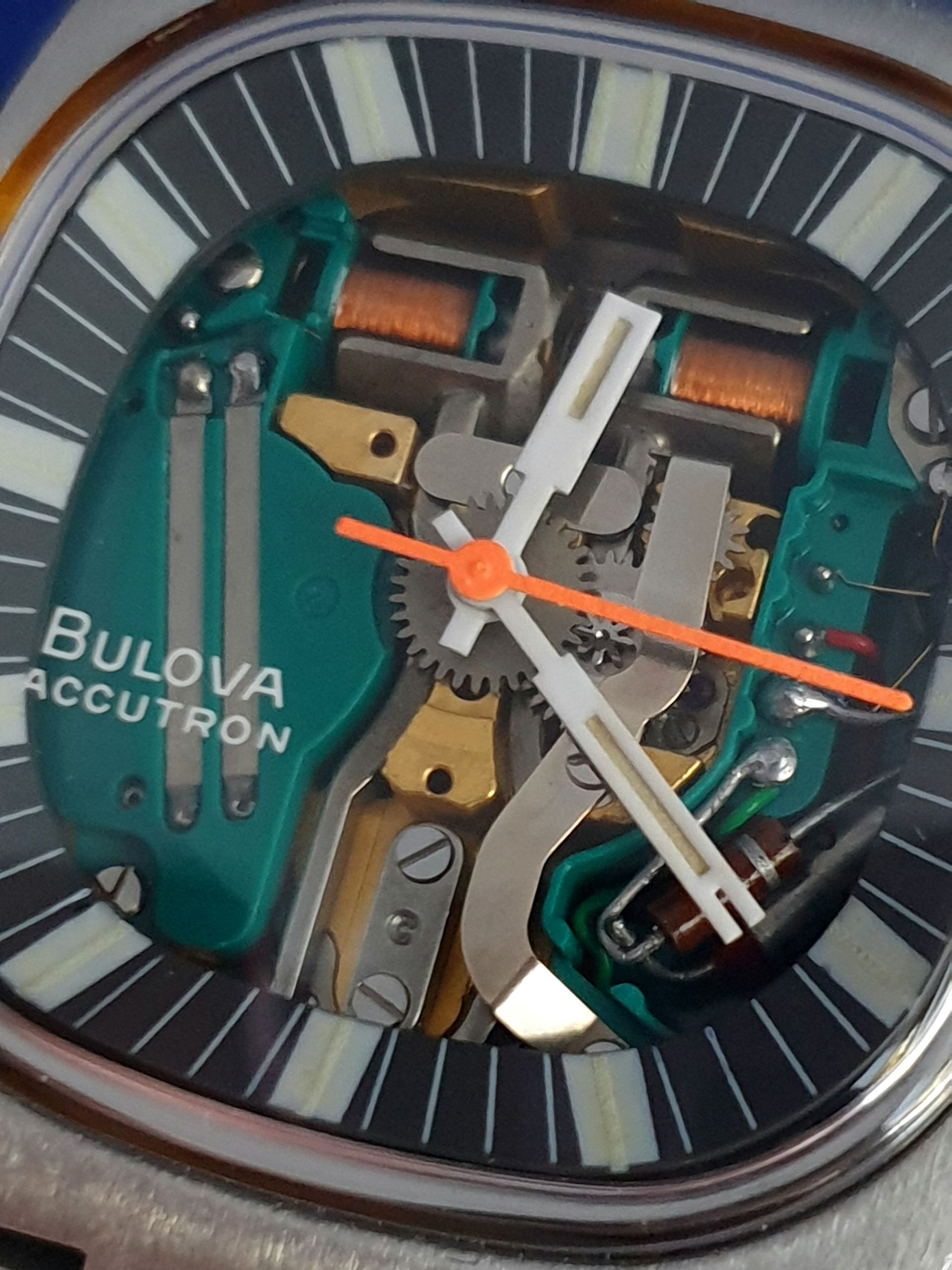 Bulova Accutron watch dial with exposed inner mechanics and orange second hand