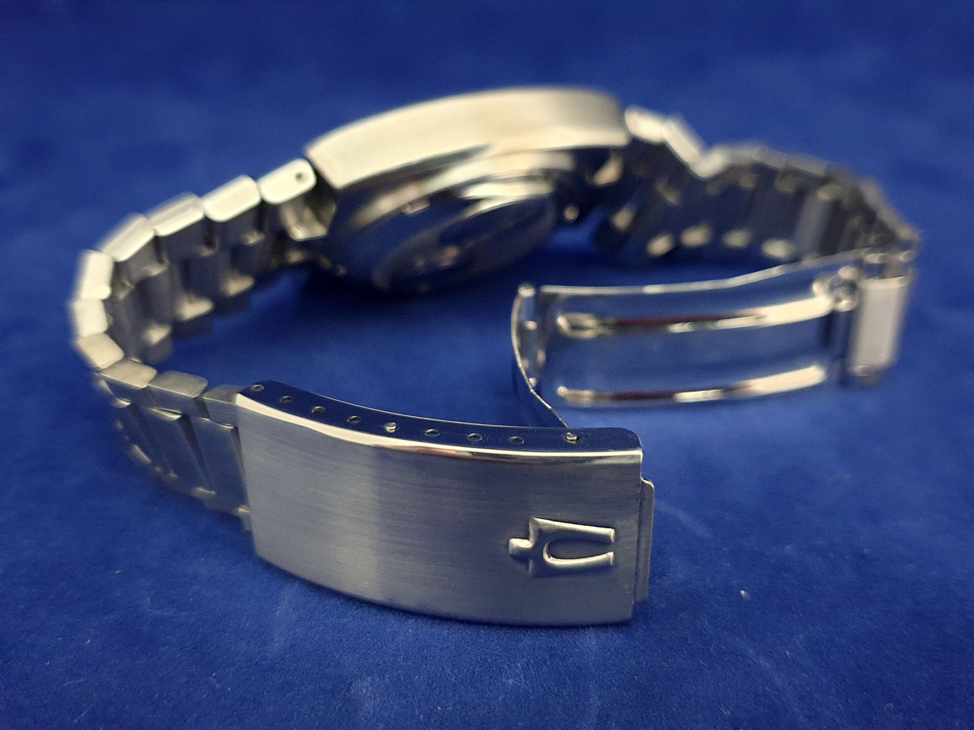 Silver wristwatch with metal band on a blue background