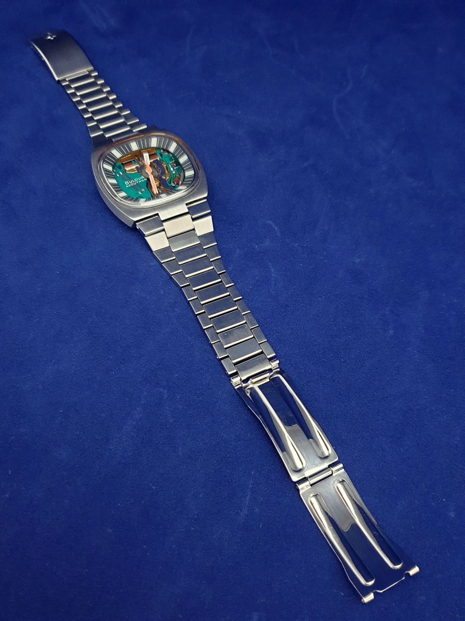 Silver wristwatch with open transparent case on a blue background