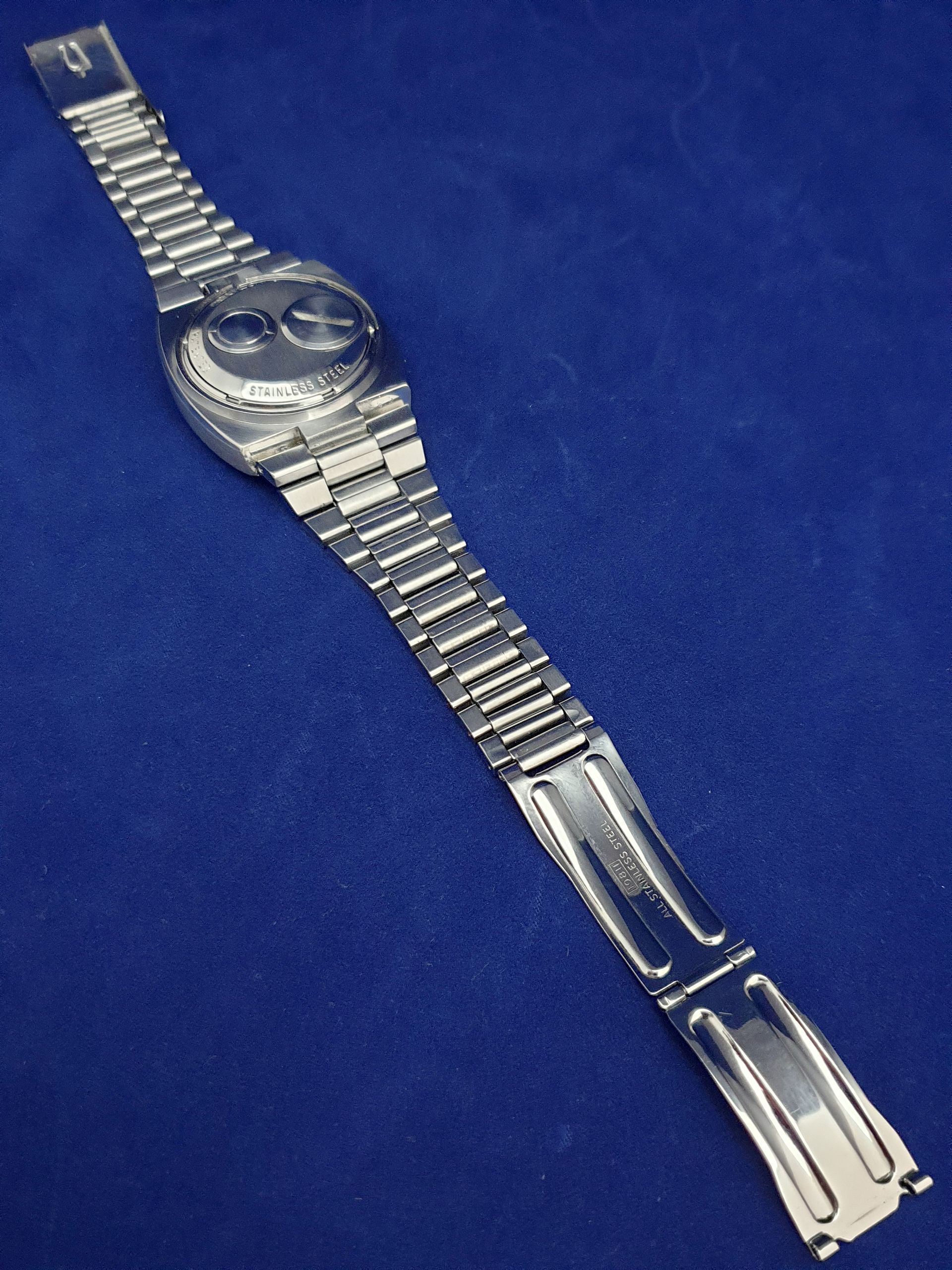 Silver wristwatch with metal link band on a blue background