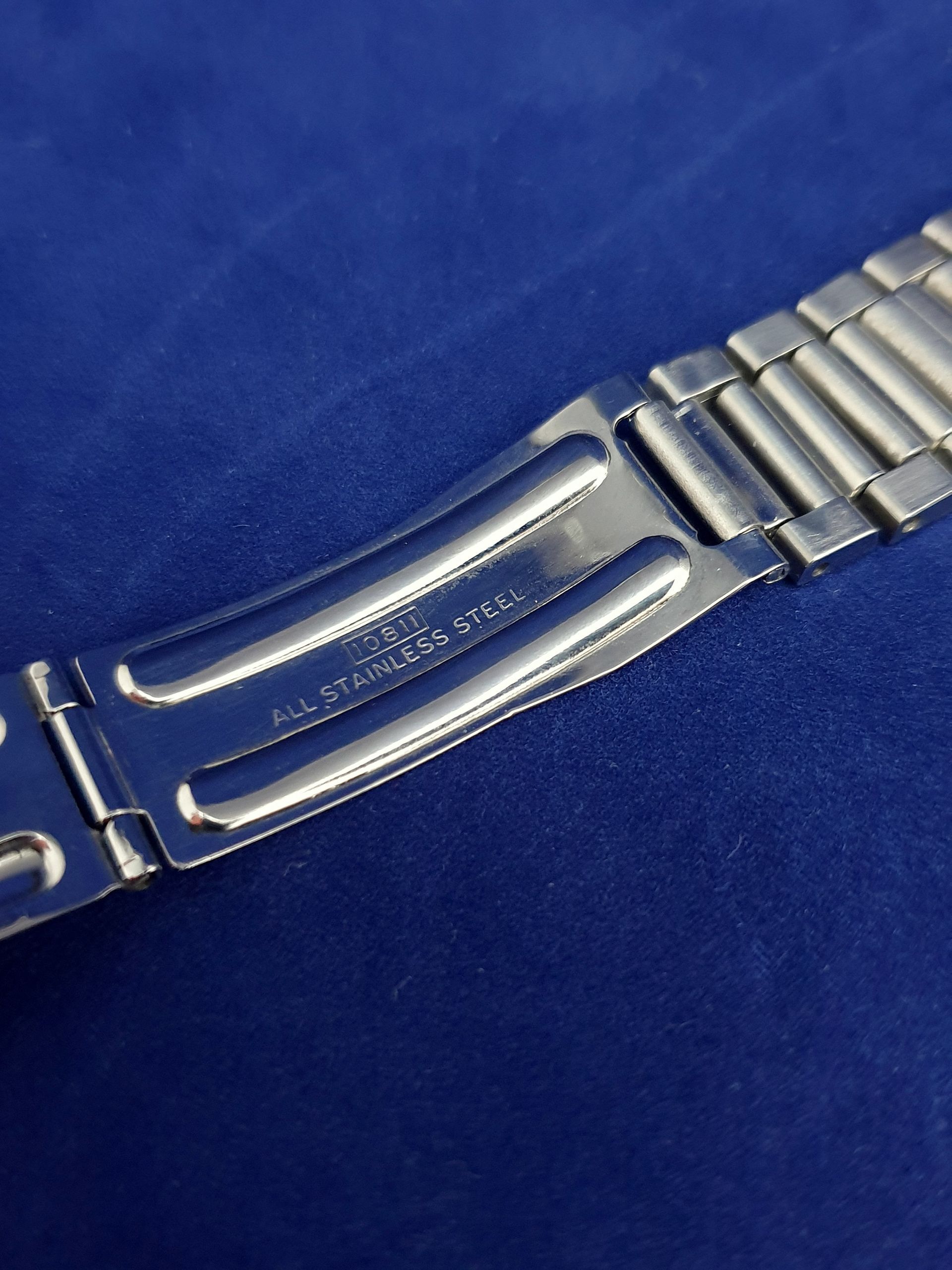 Close-up of a silver metal watch clasp on a blue background