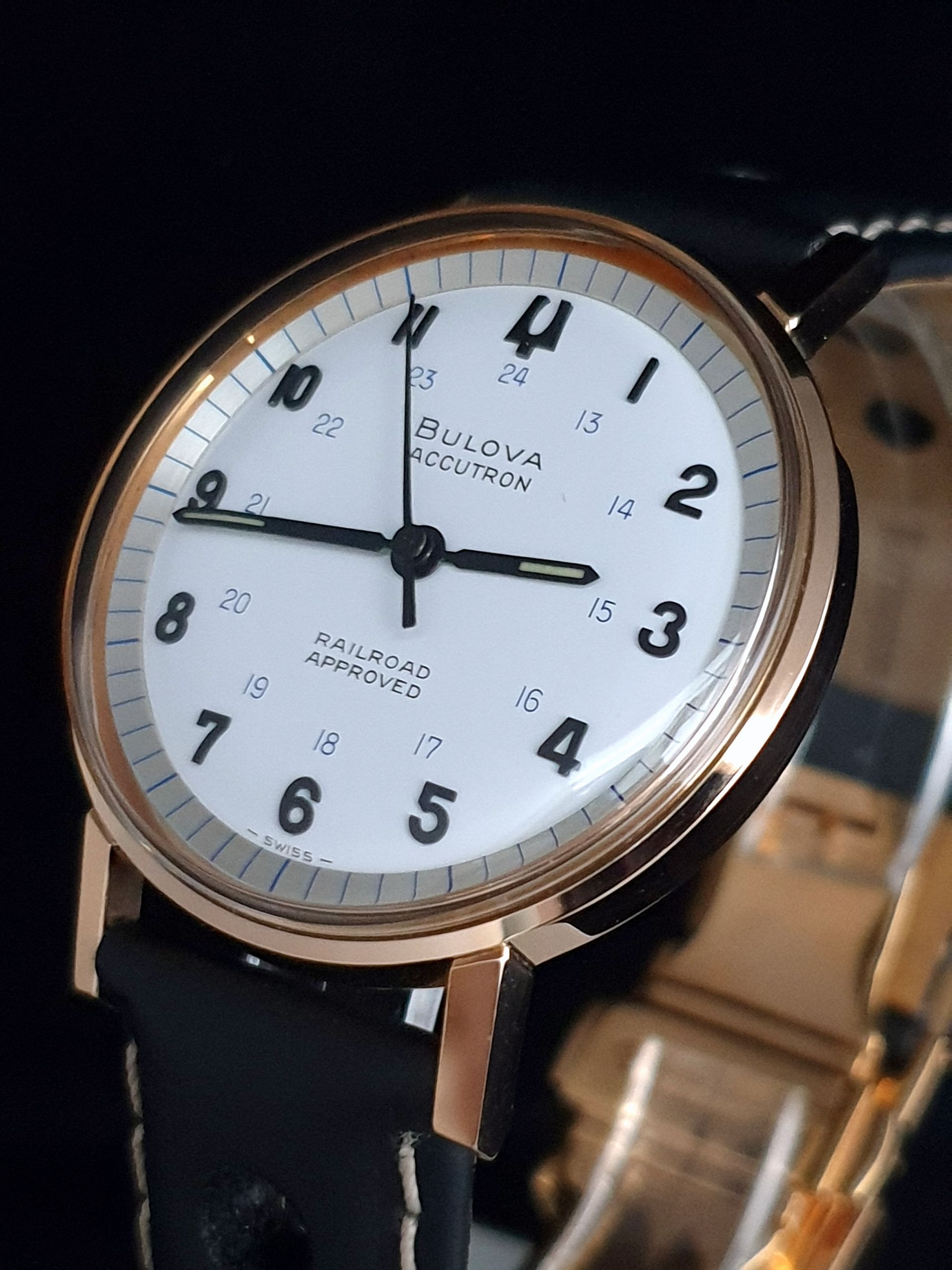Close-up of a Bulova wristwatch with a white dial, black leather strap, and rose-gold case