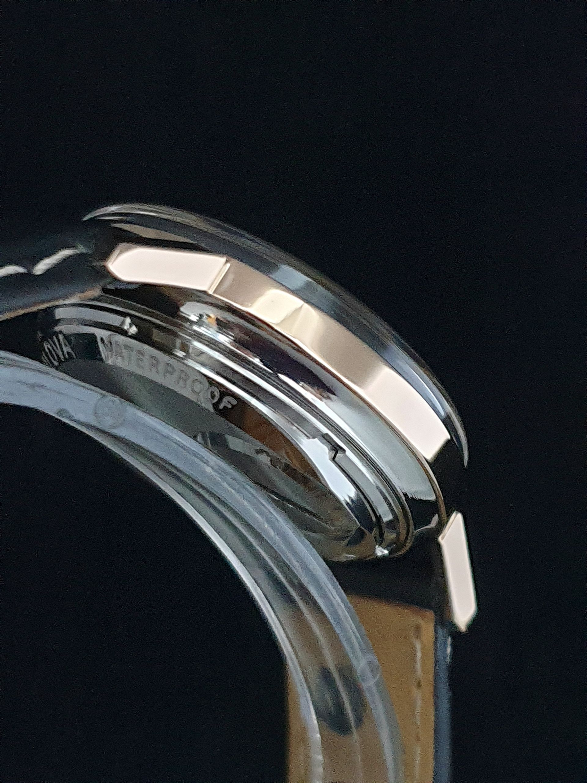 Close-up of a silver wristwatch with a clear band against a dark background