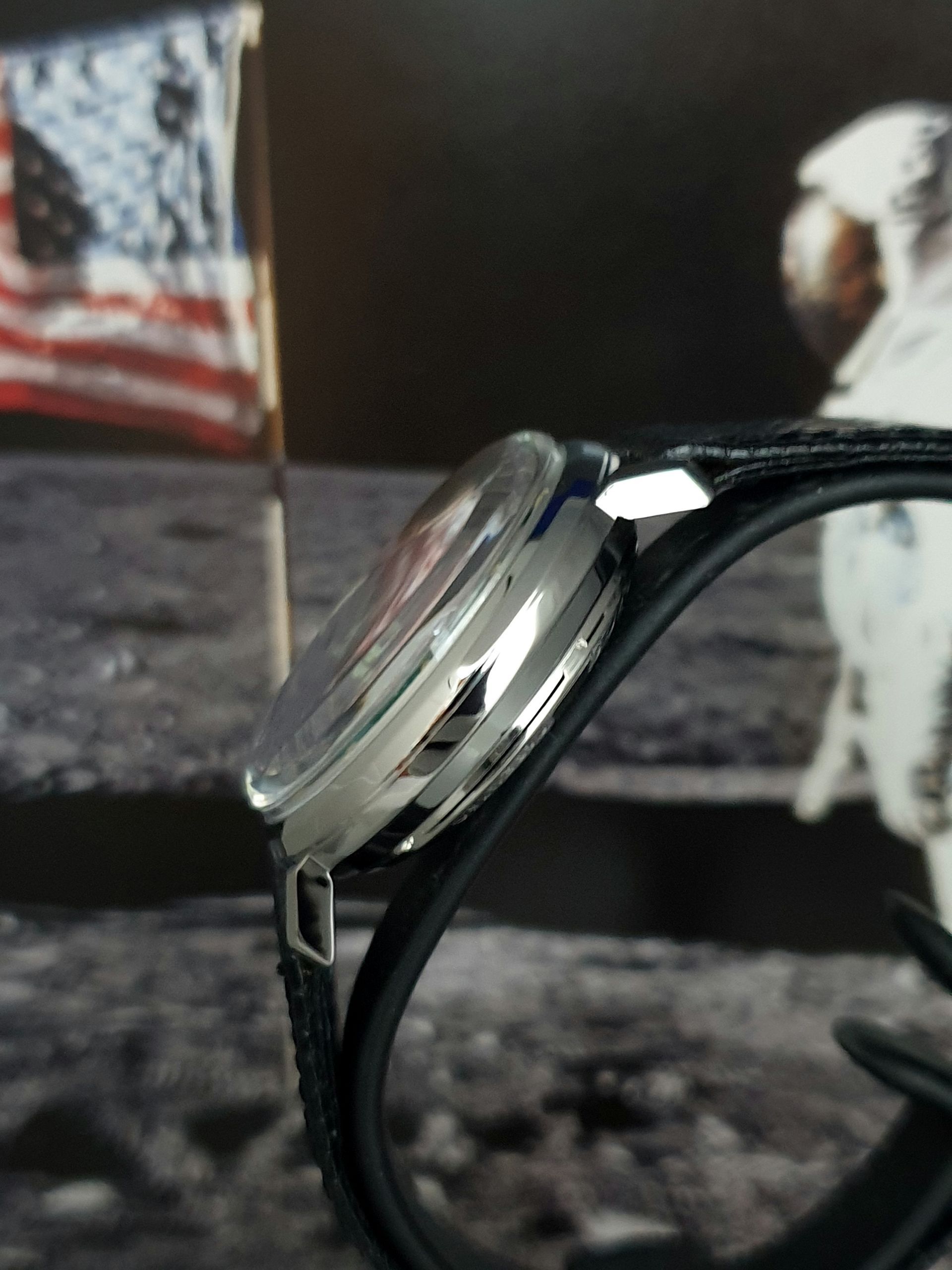 Close-up of black-framed glasses on a table with a blurred American flag in the background