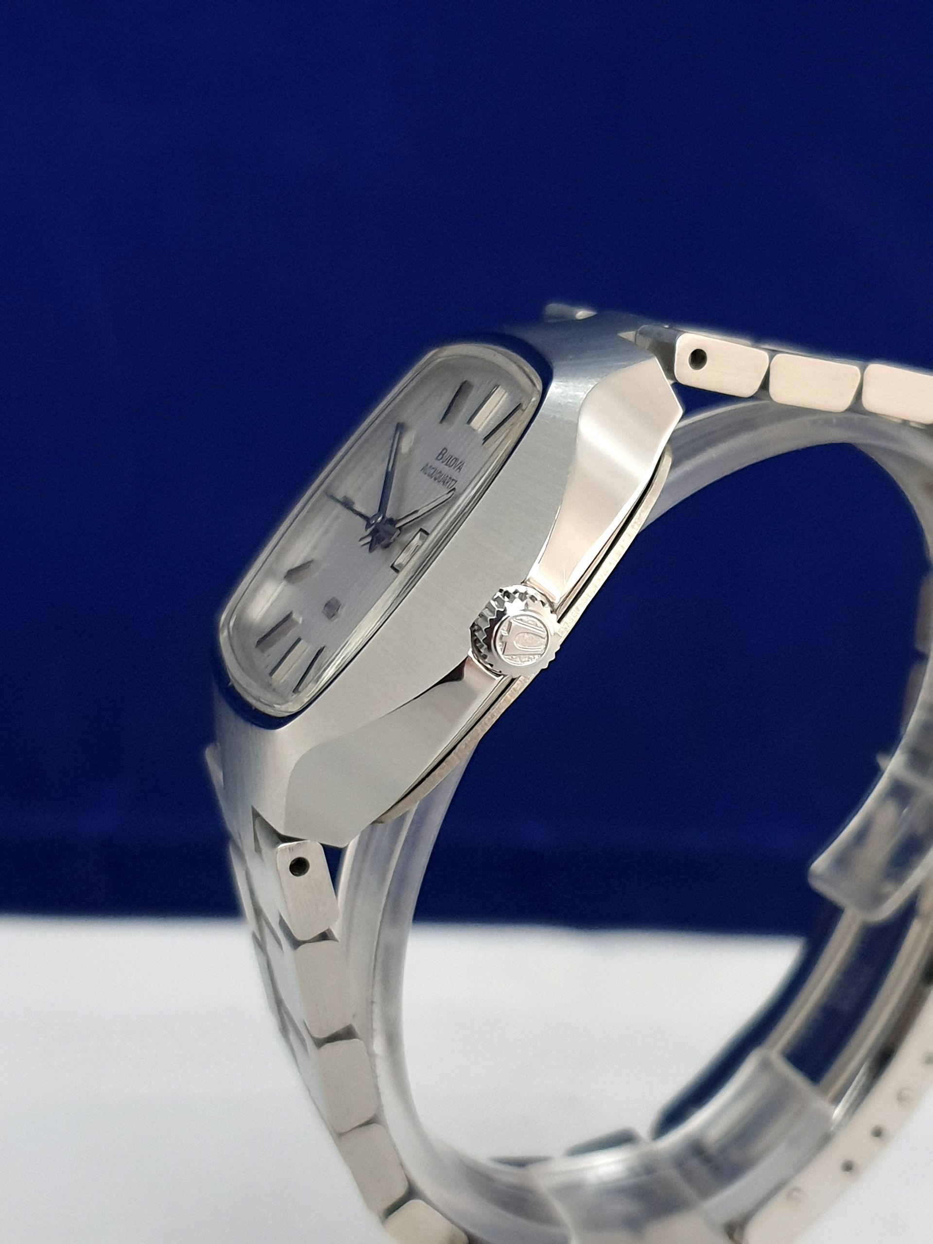 Silver wristwatch on a white surface against a blue background