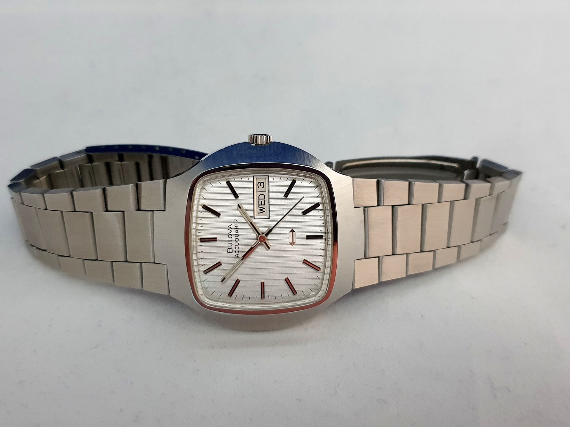 Stainless steel wristwatch with a white square face and silver bracelet, centered on a plain background