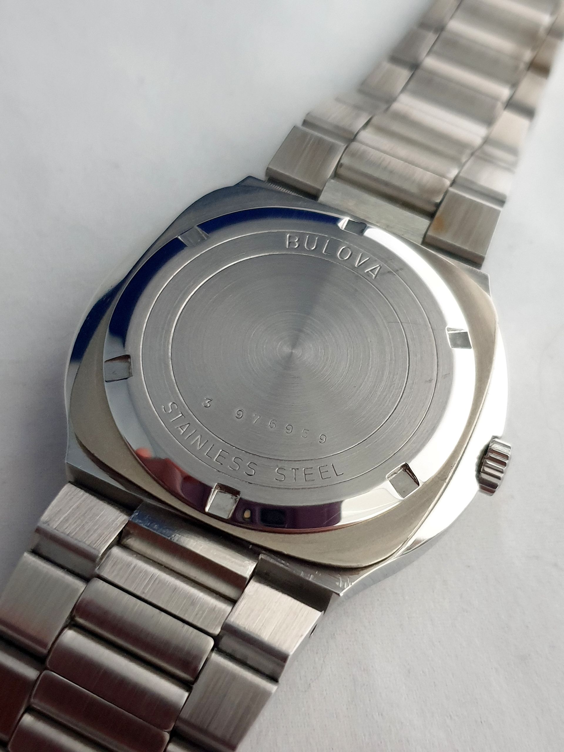 Silver metal wristwatch shown from the back on a light surface