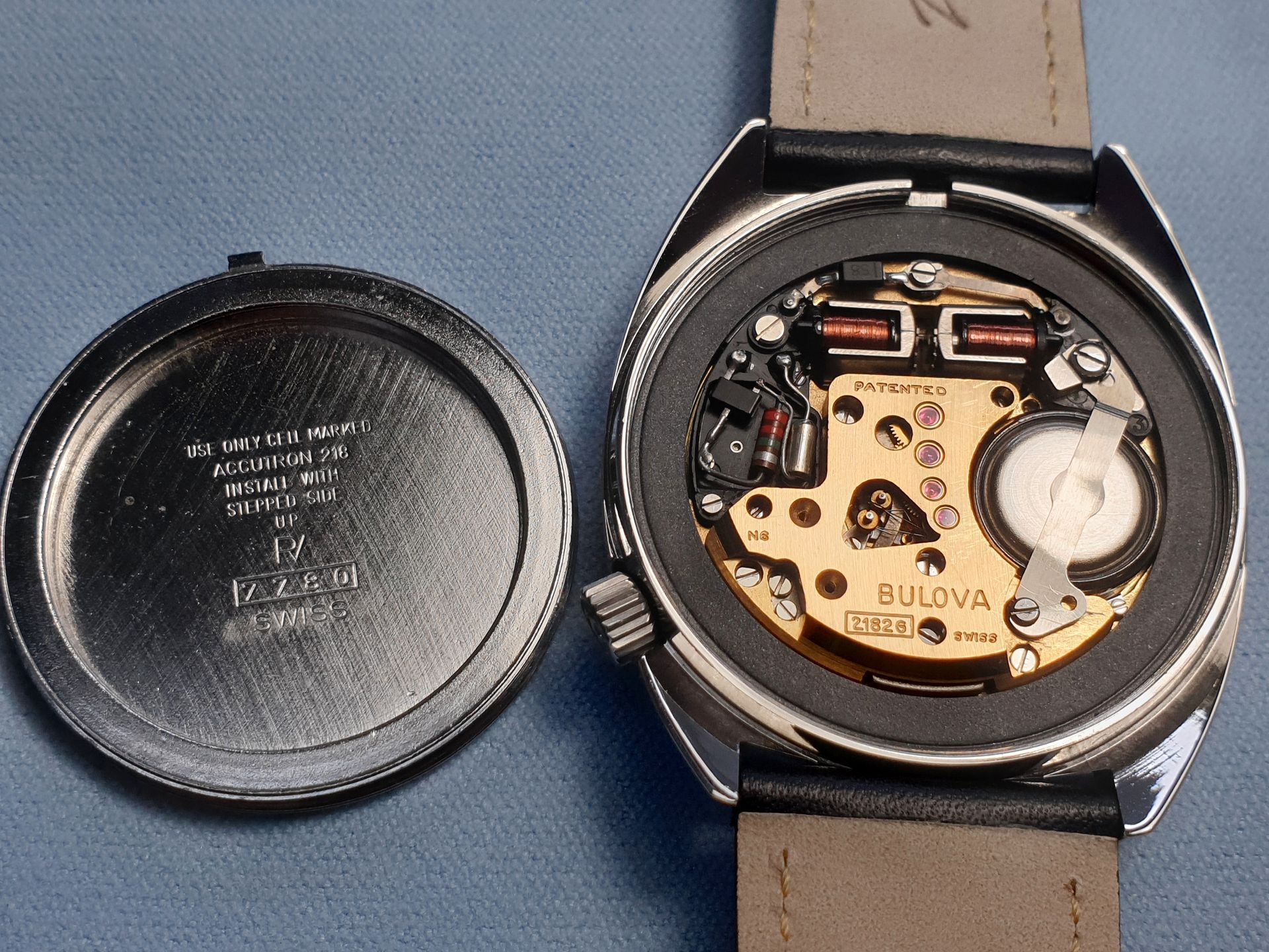 Open wristwatch with exposed Bulova movement beside its removed caseback cover