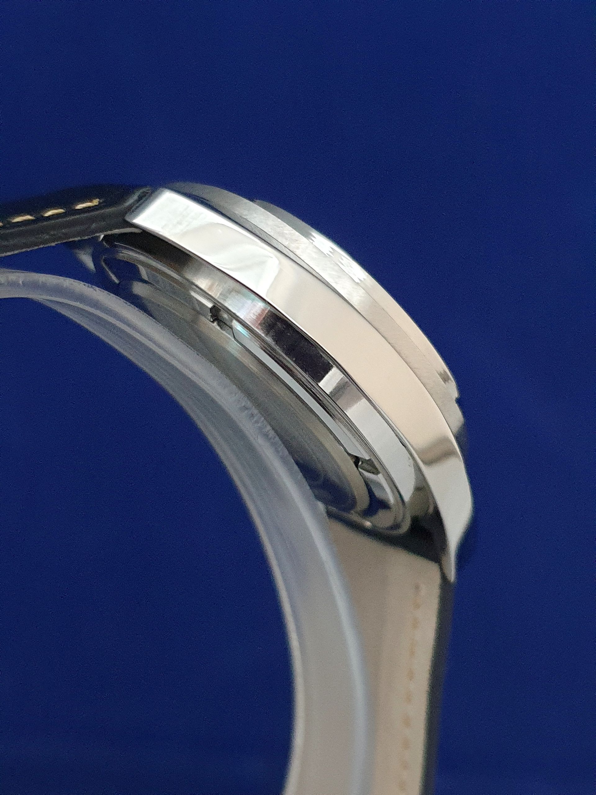 Close-up of a silver wristwatch with a white face and metal band on a blue background
