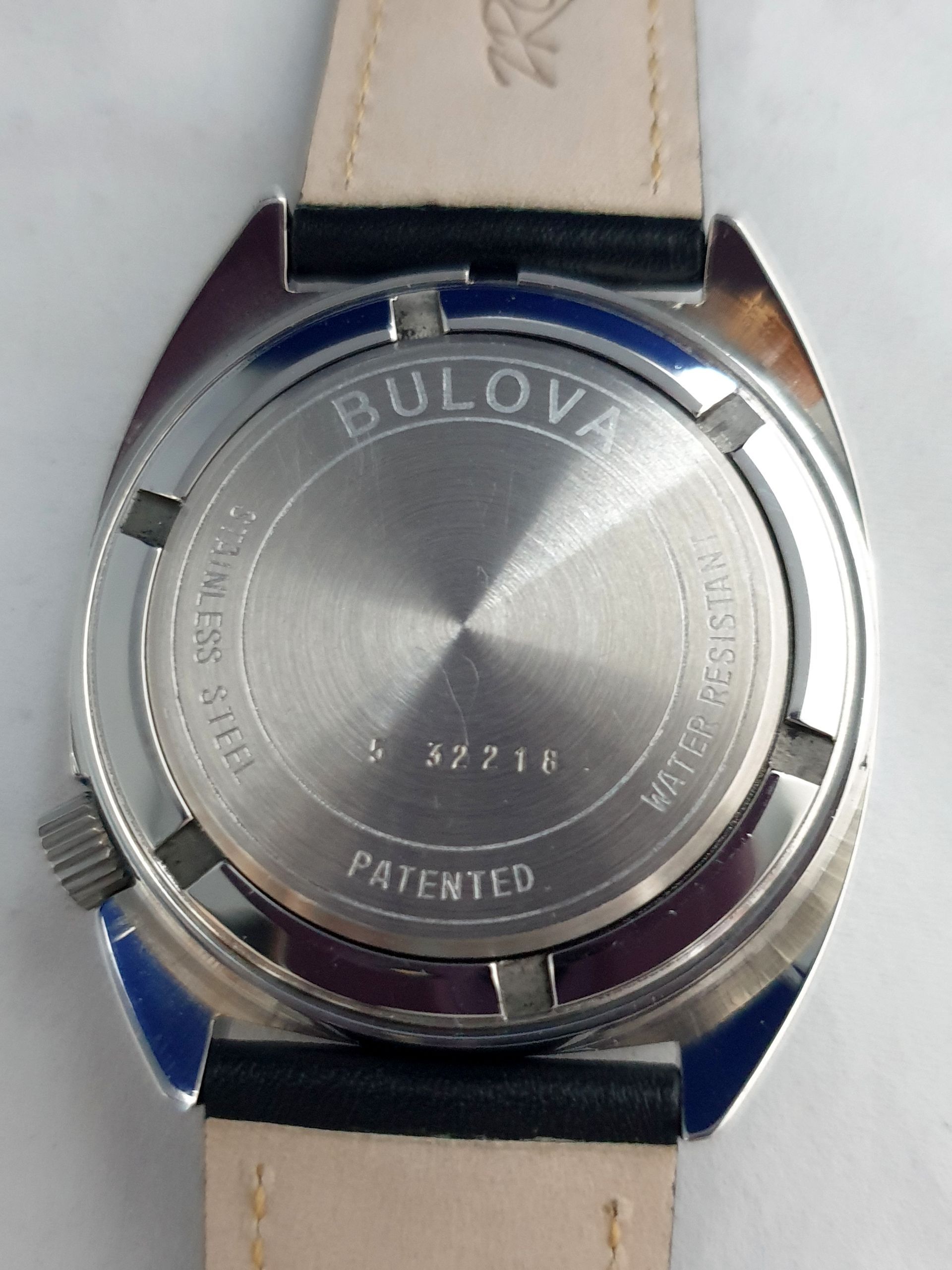 Close-up of a Bulova watch’s stainless steel case back with leather strap attached