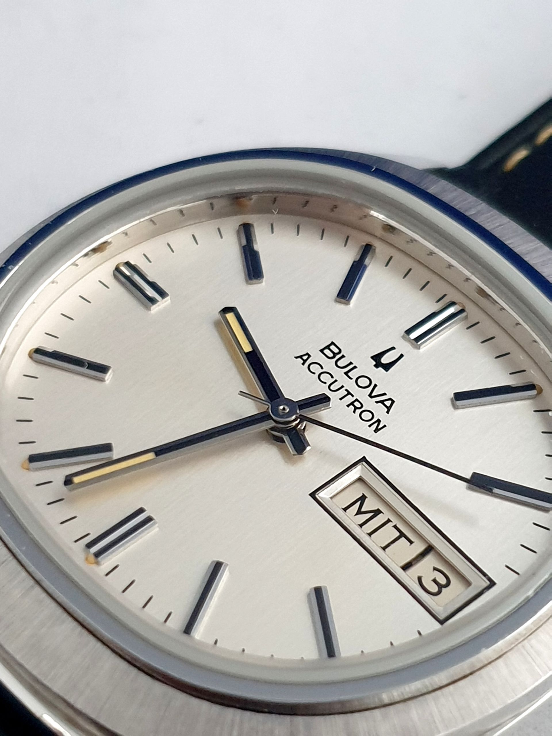 Close-up of a silver Bulova Accutron watch showing 11:13 and Friday 13 on the date window