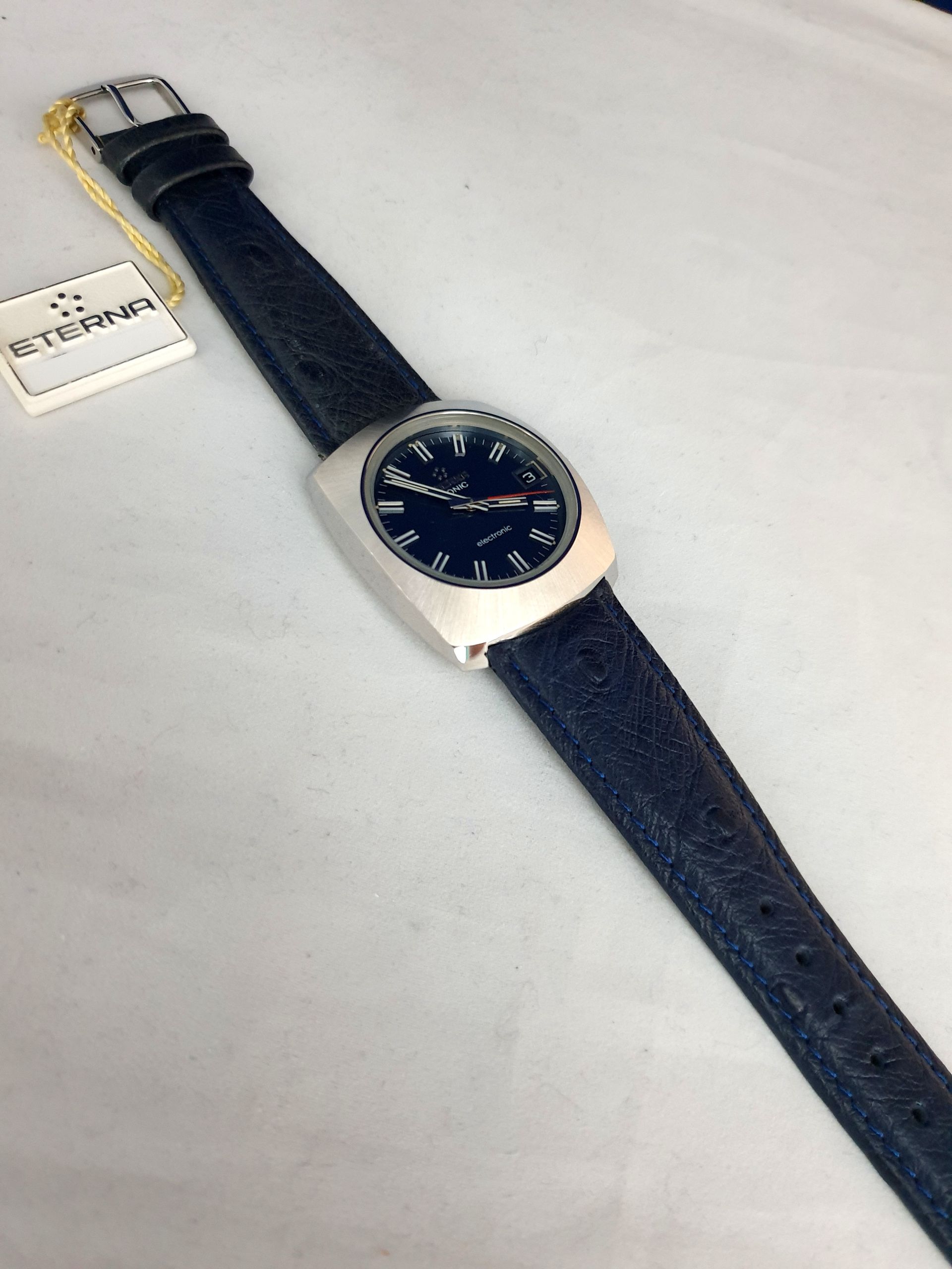 Blue leather wristwatch with silver case and navy dial on a white background