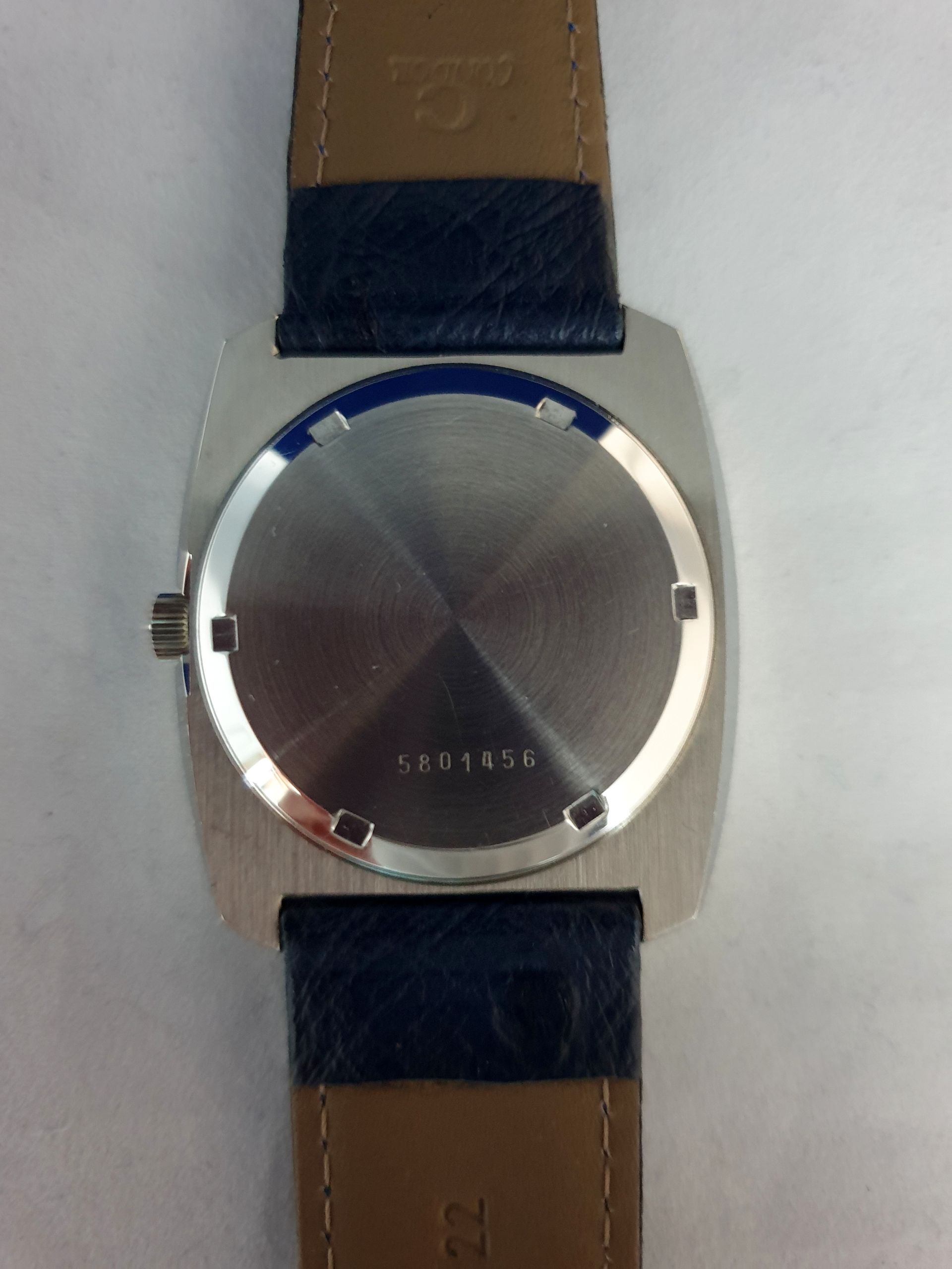 Silver wristwatch with a brown leather strap on a light background