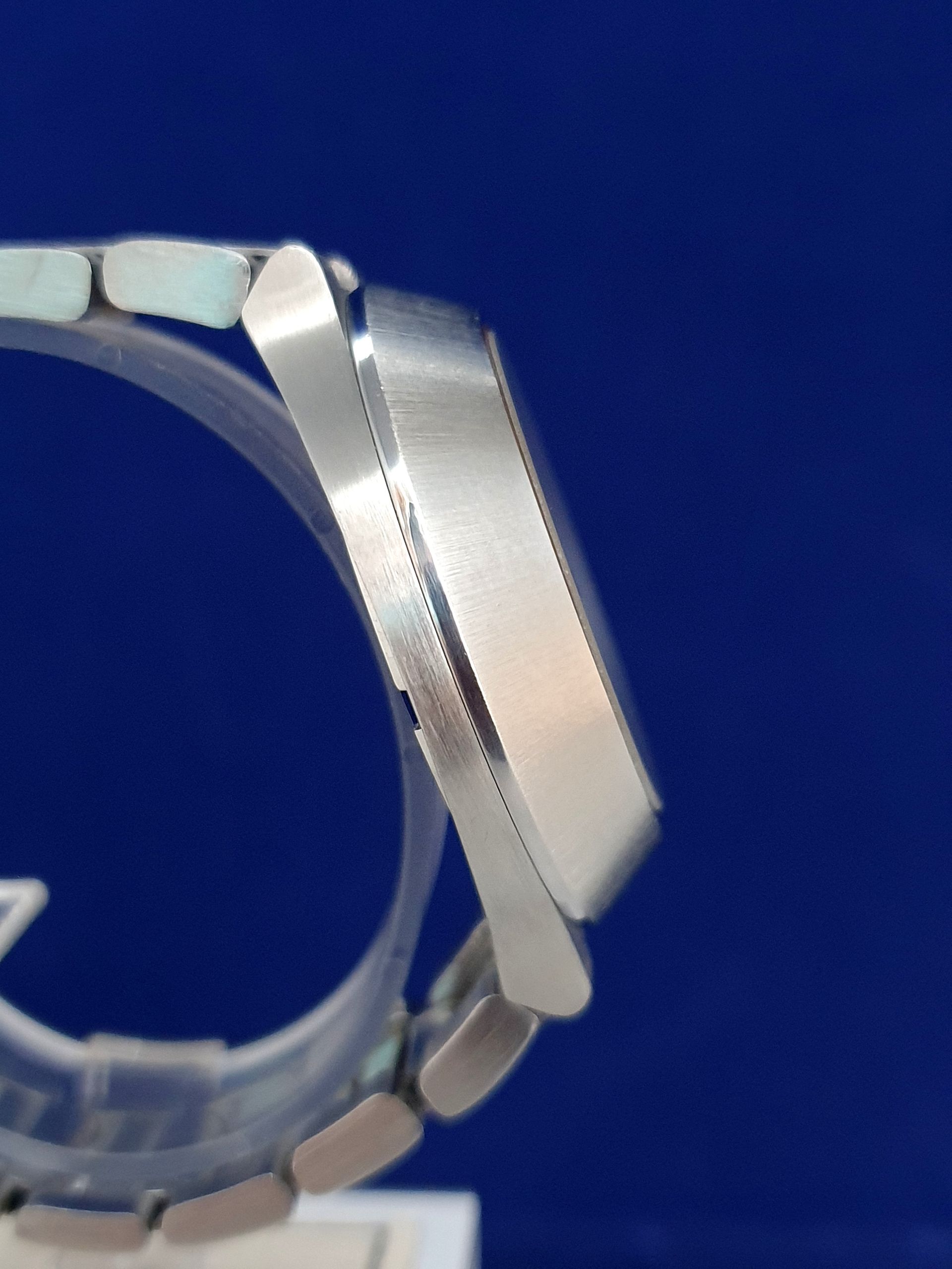Close-up of a silver wristwatch side profile against a blue background