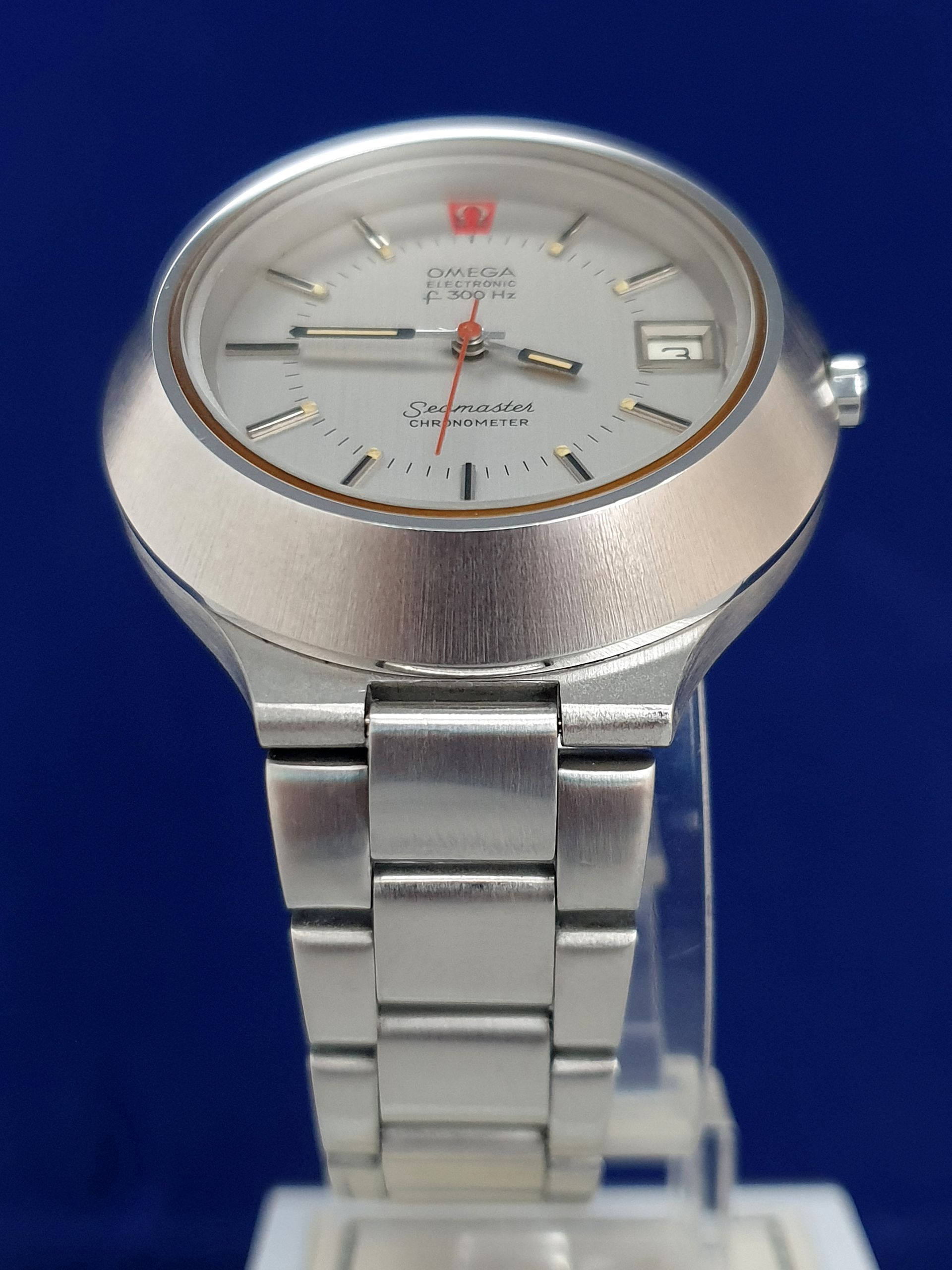 Silver wristwatch with round face and metal band on a blue background