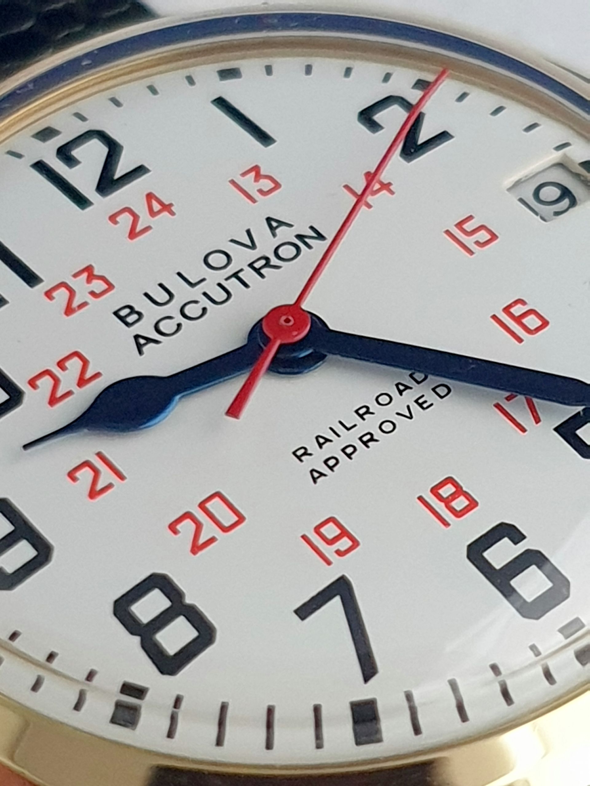 Close-up of a Bulova Accutron watch face with black, red, and blue markings.