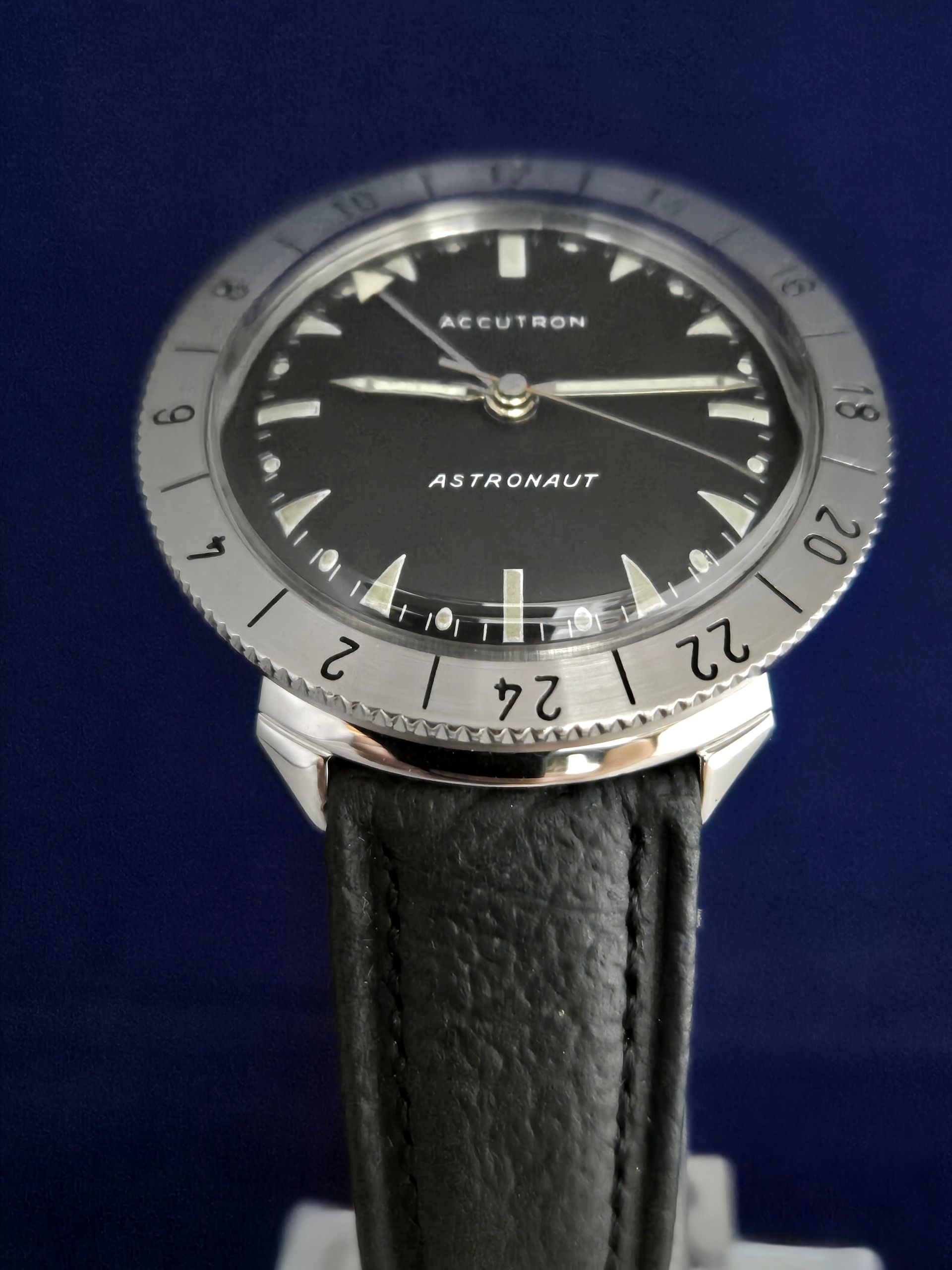 Close-up of an Aeronaut watch with a black dial and silver bezel on a black leather strap.