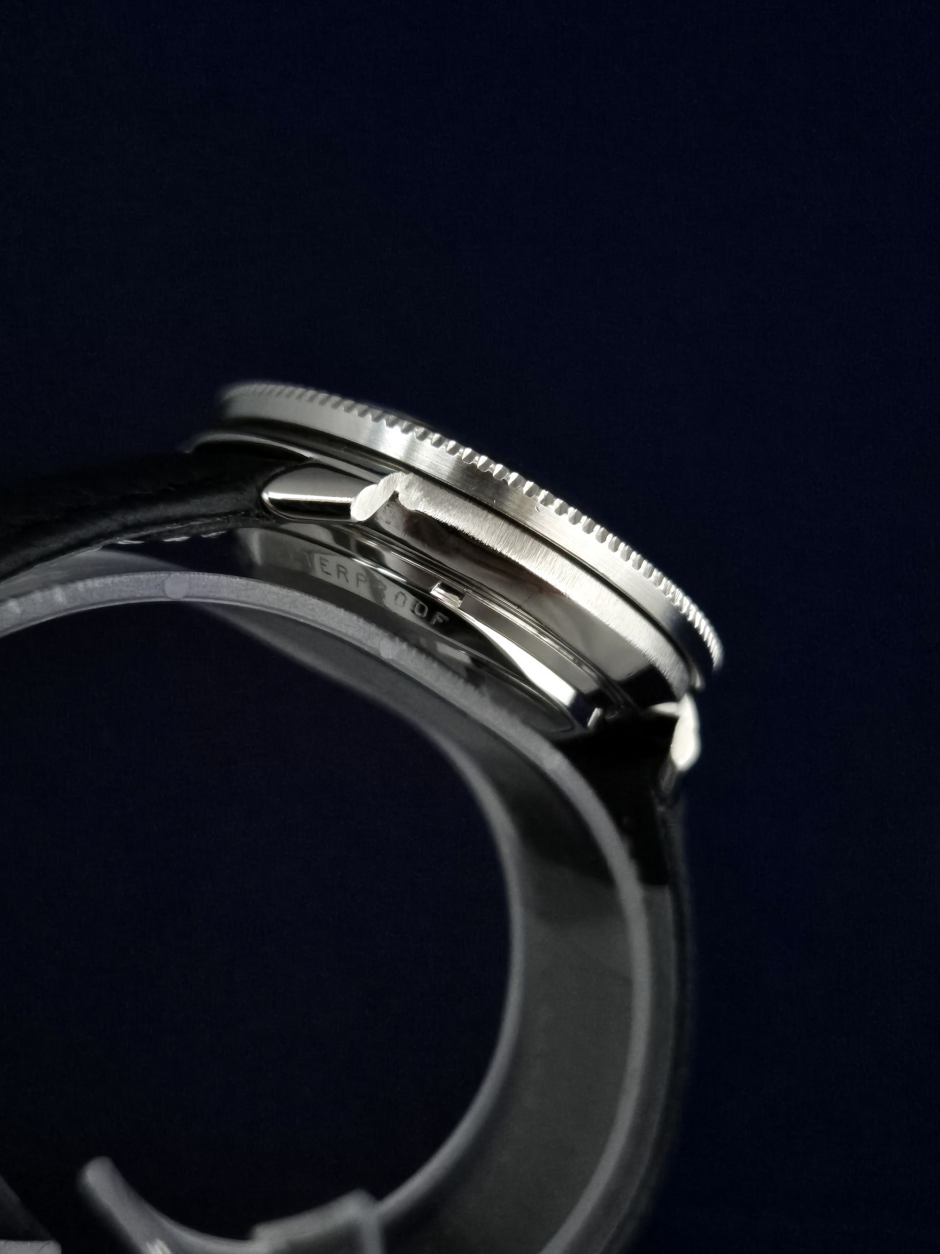Close-up of a silver wristwatch on a black band against a dark background