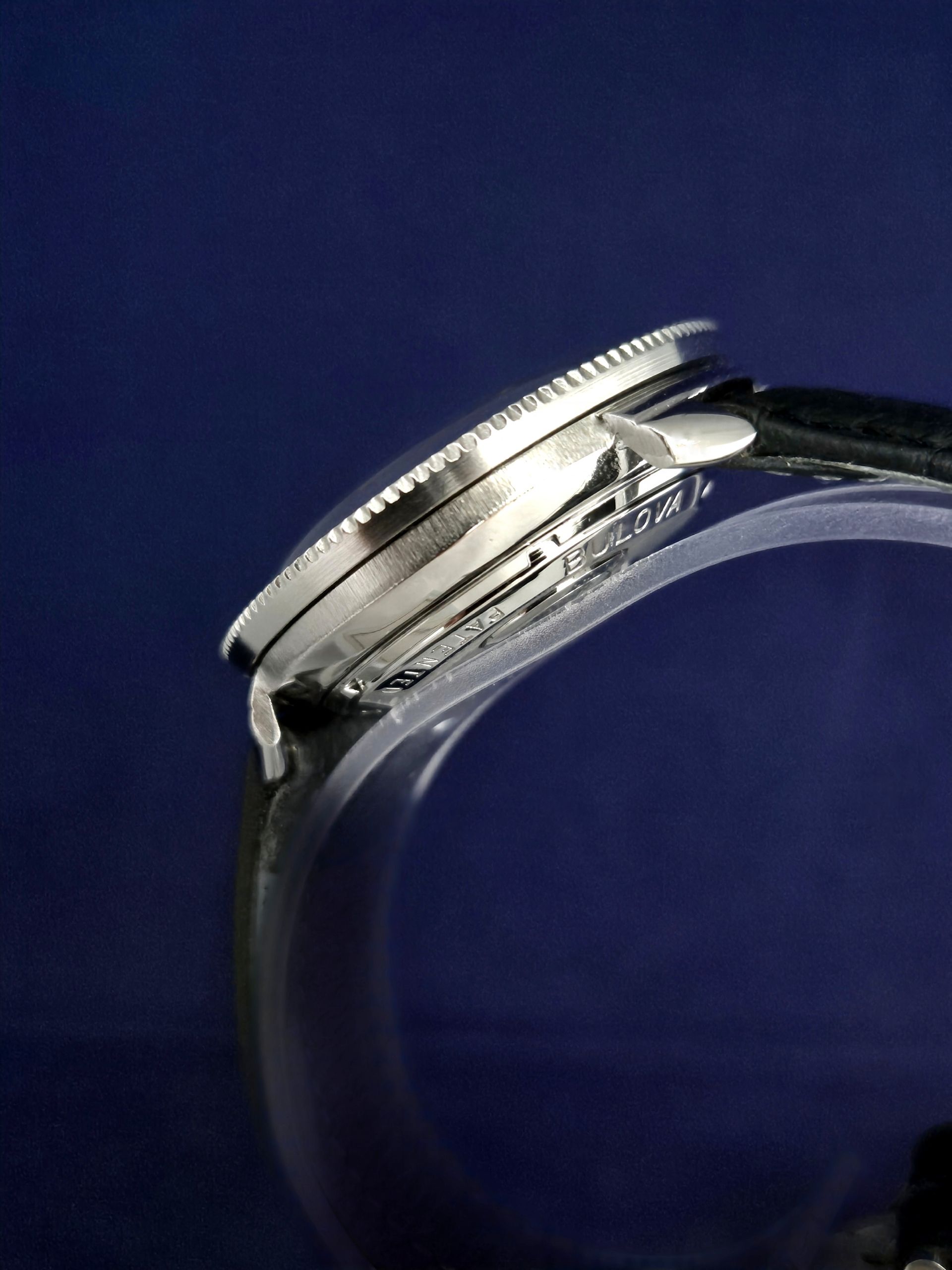 Close-up of a silver wristwatch on a dark blue background