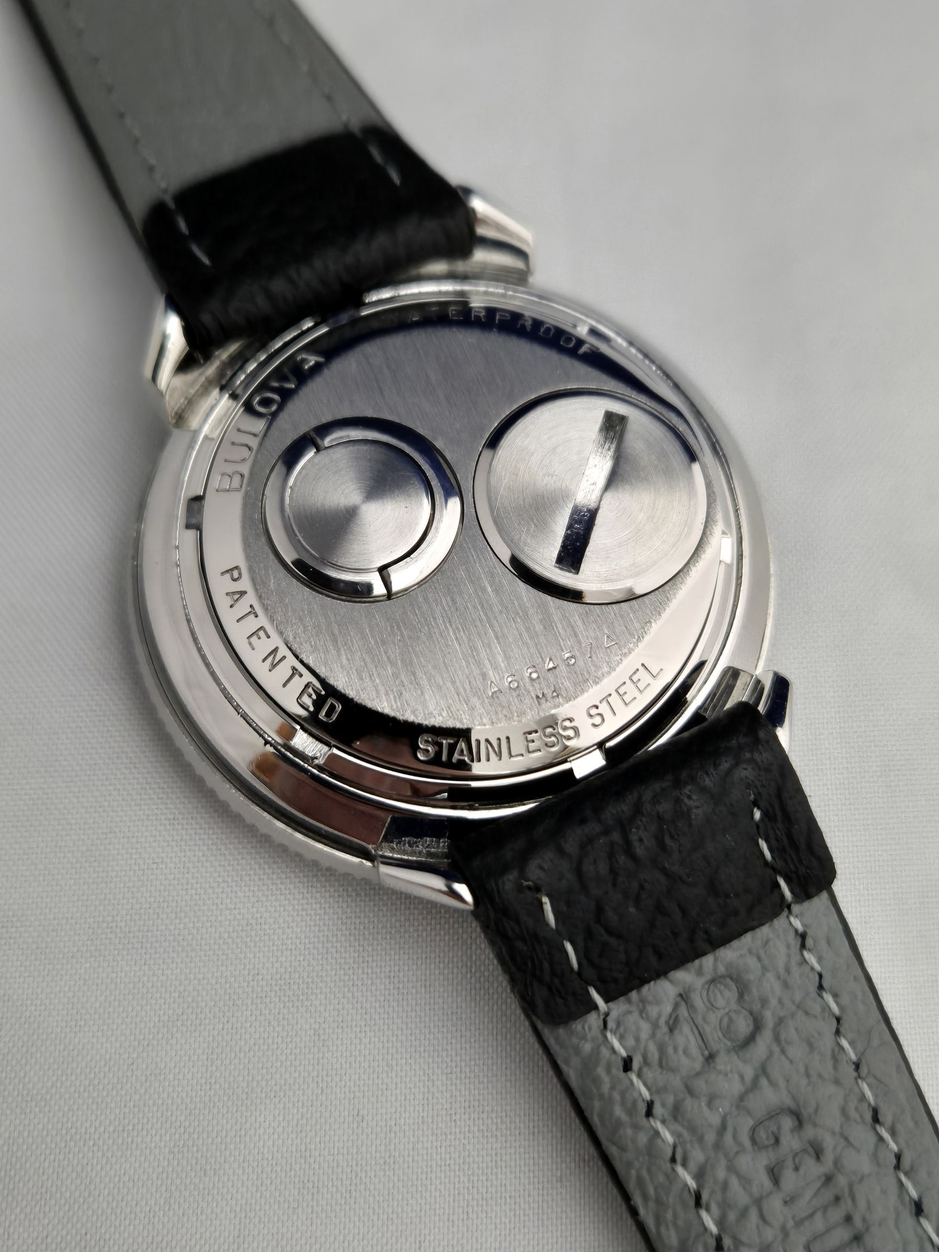 Close-up of a silver wristwatch with a black leather strap and two circular dials.