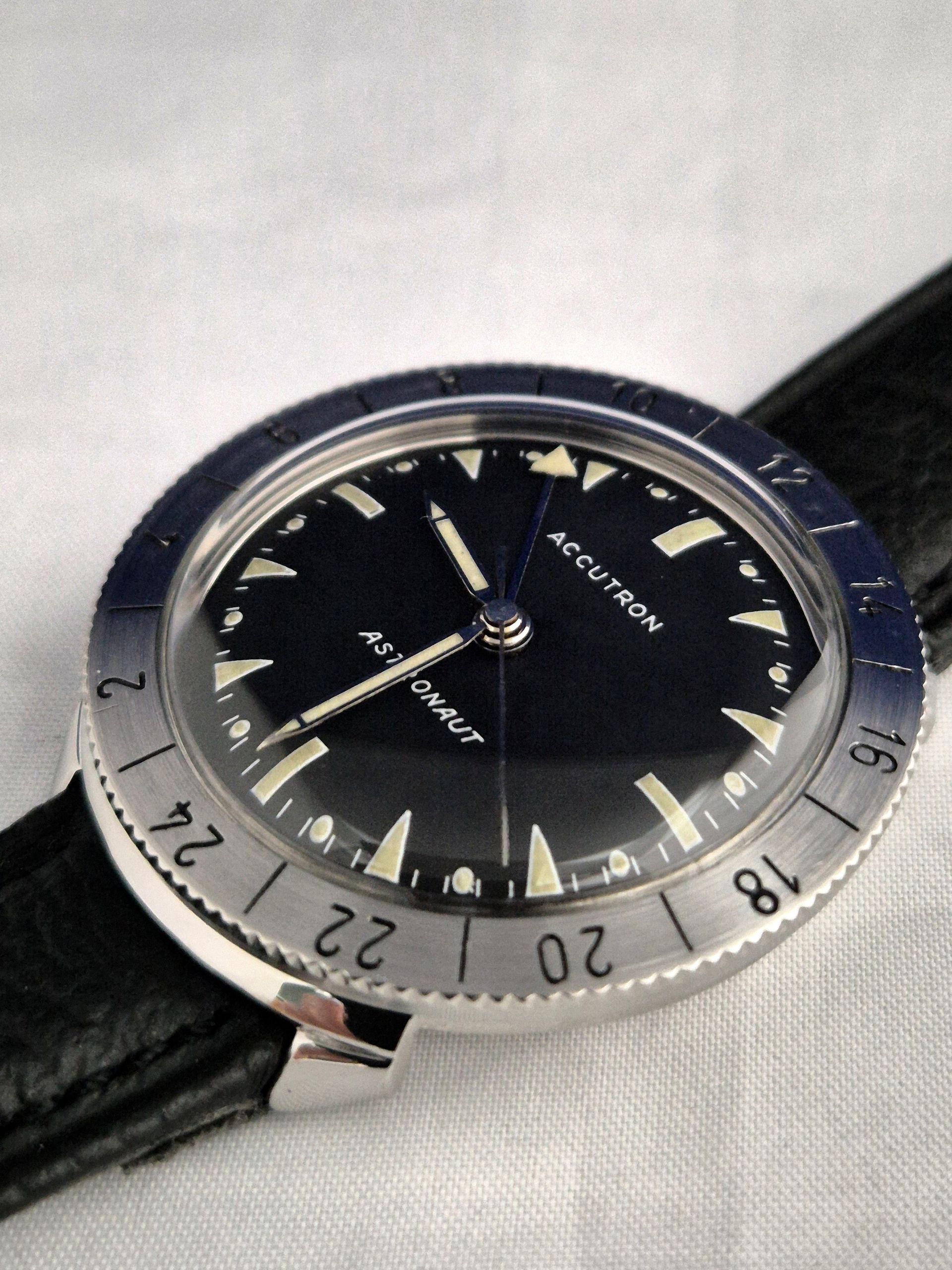 Close-up of a black and silver analog wristwatch with a leather strap
