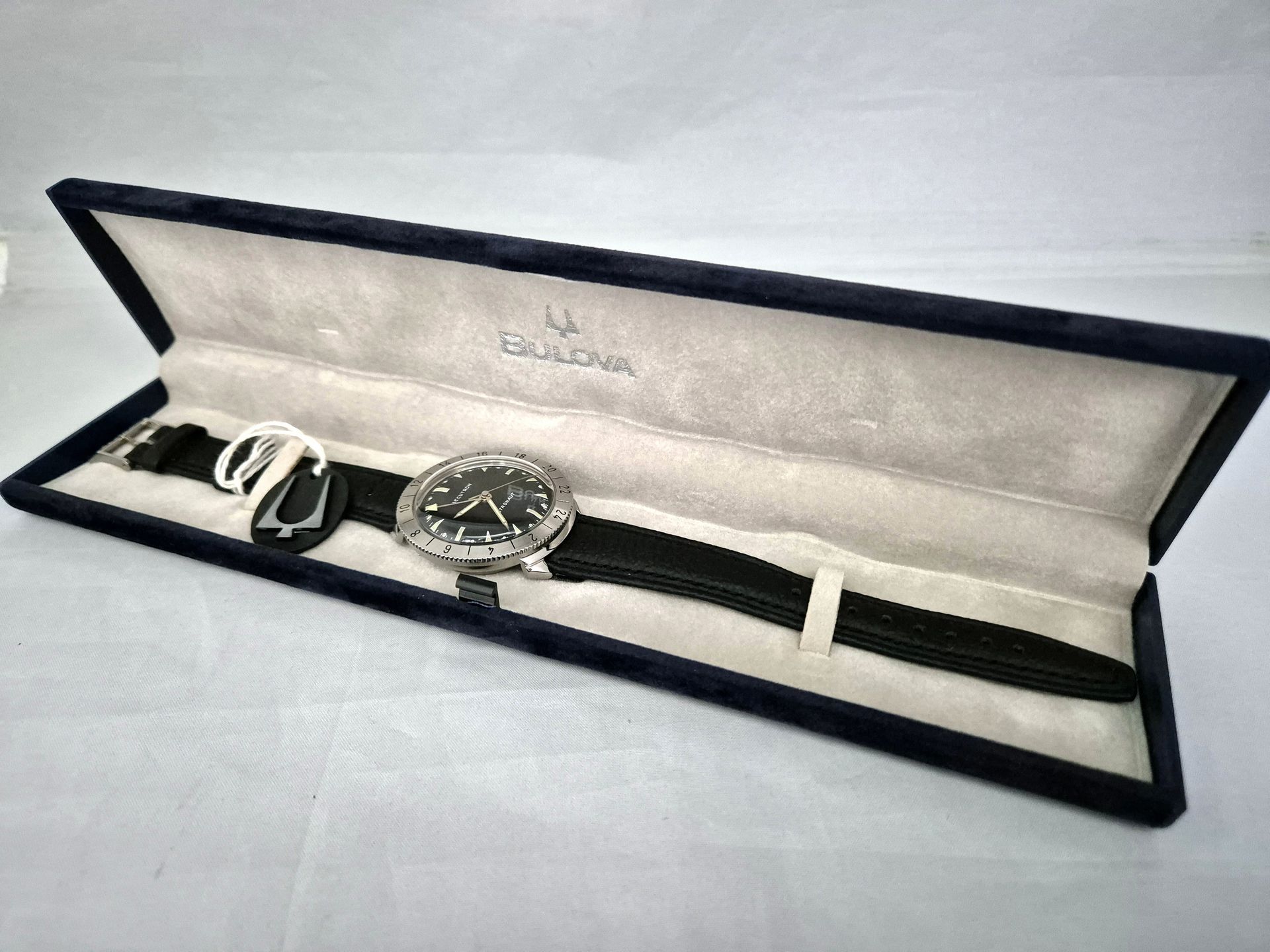 Black wristwatch displayed in an open velvet presentation case on a white surface
