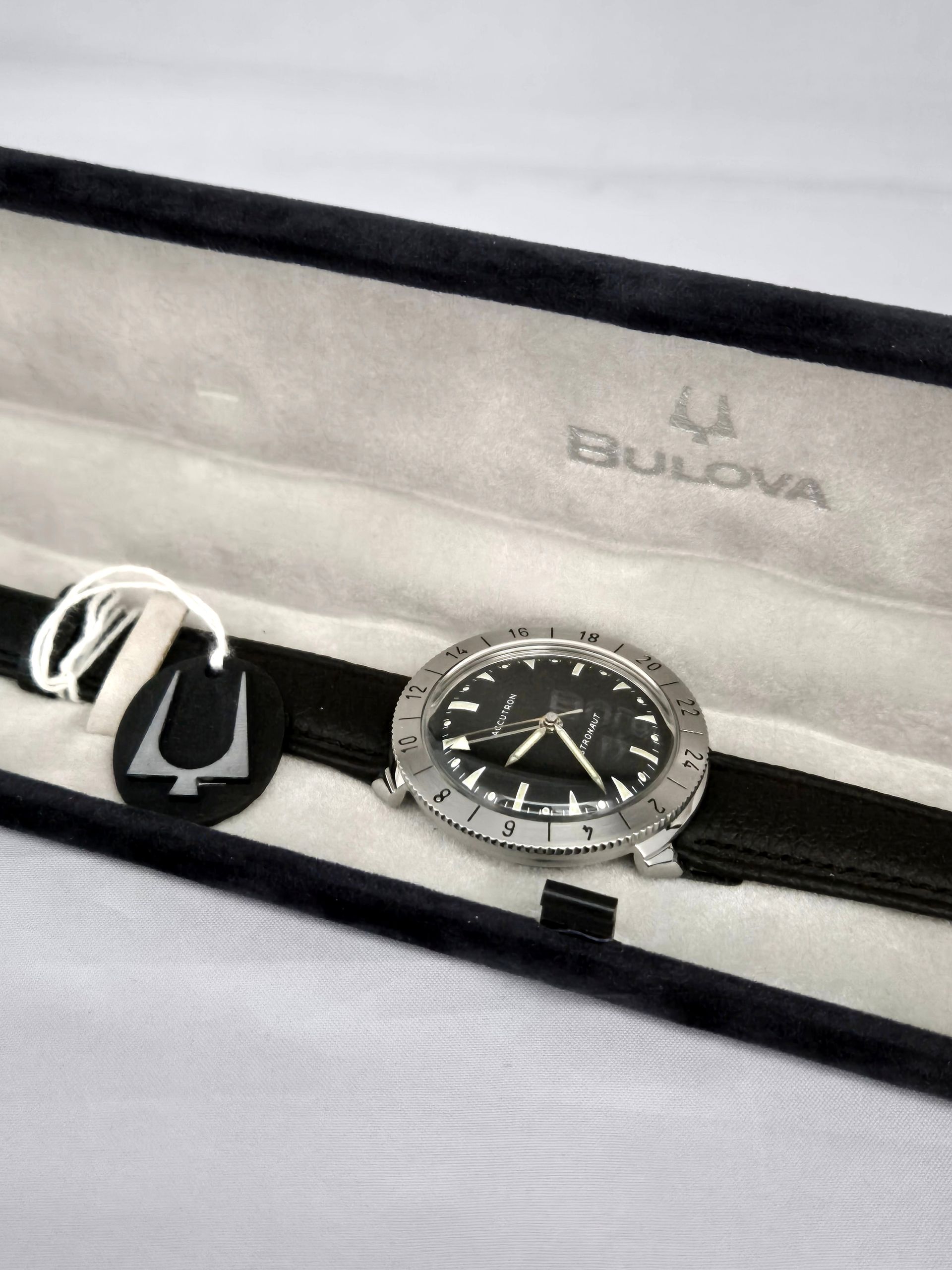 Bulova watch with black strap and tags in a display box