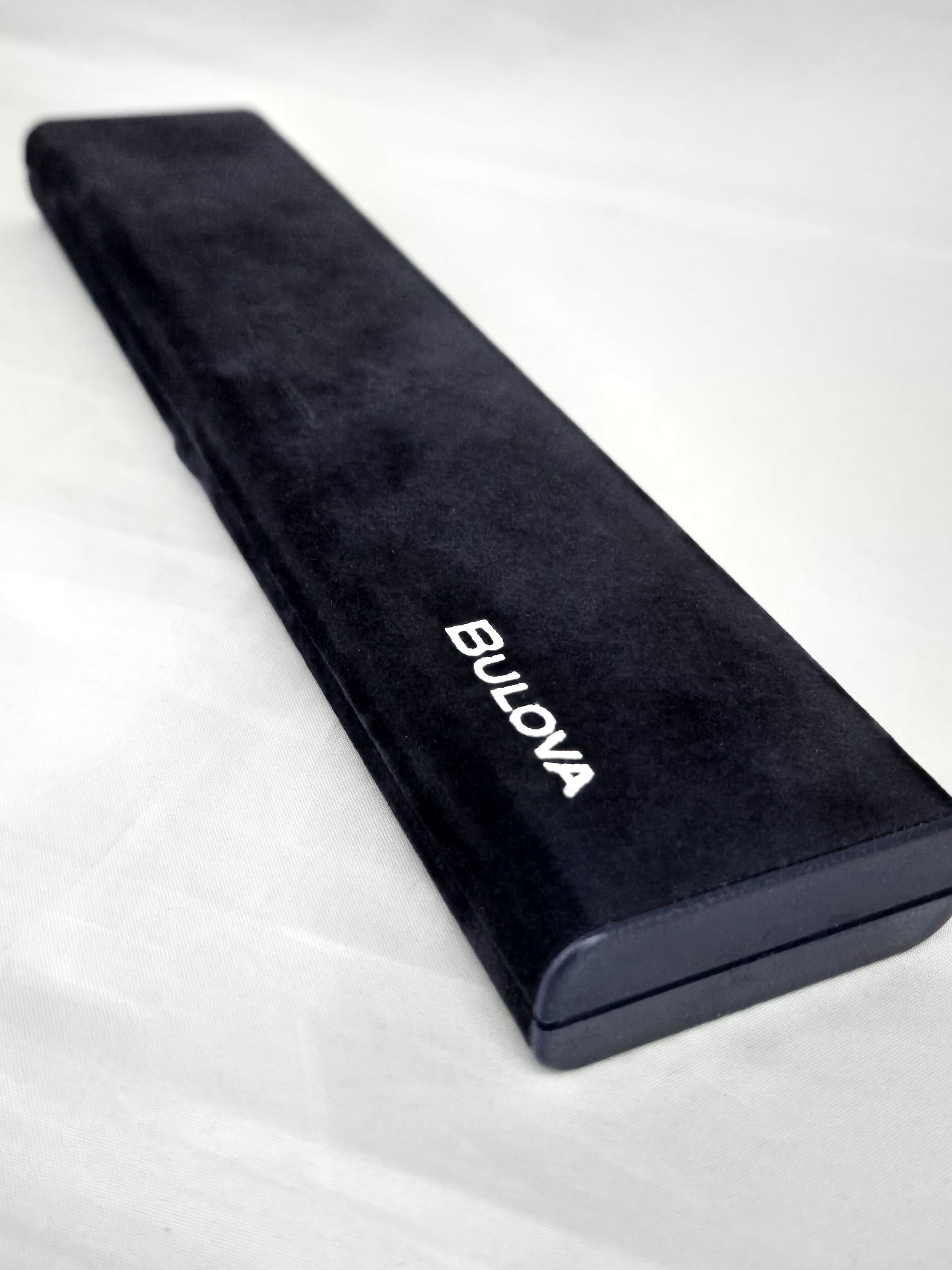 Black Bulova watch case on a white surface.