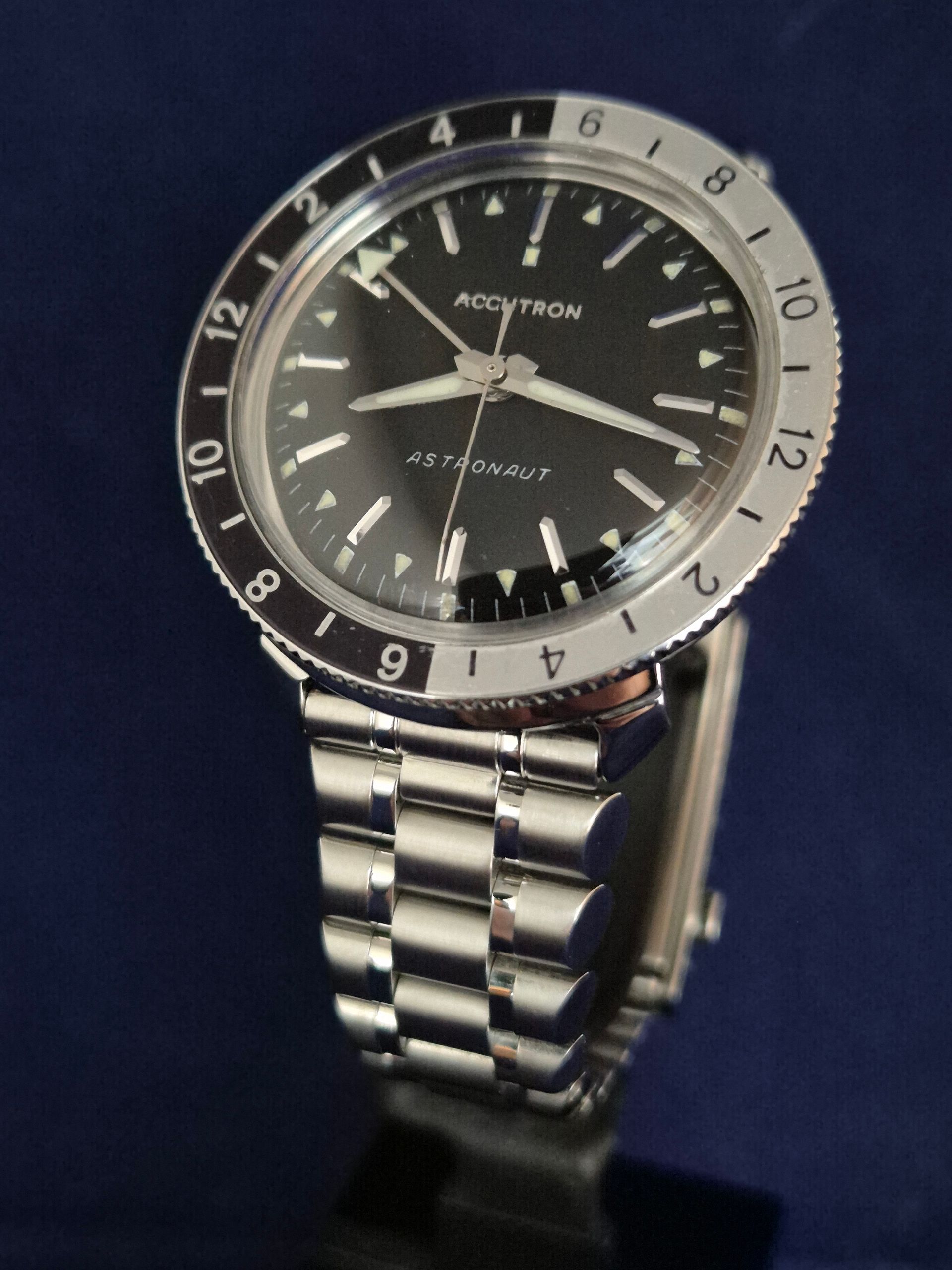 Silver wristwatch with black dial and rotating bezel on a dark background
