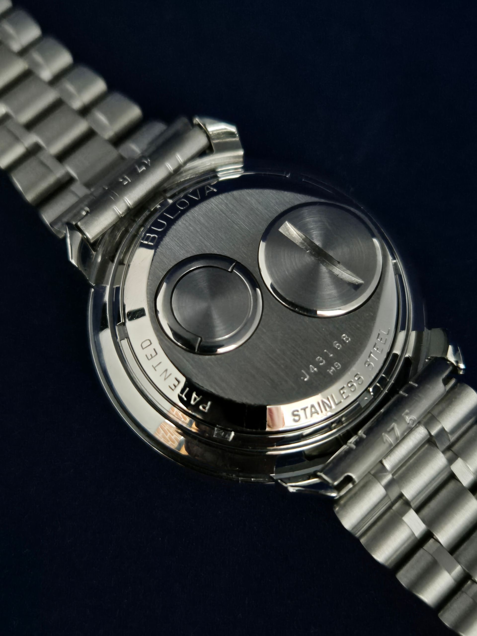 Close-up of a silver wristwatch with dual dials on a dark background