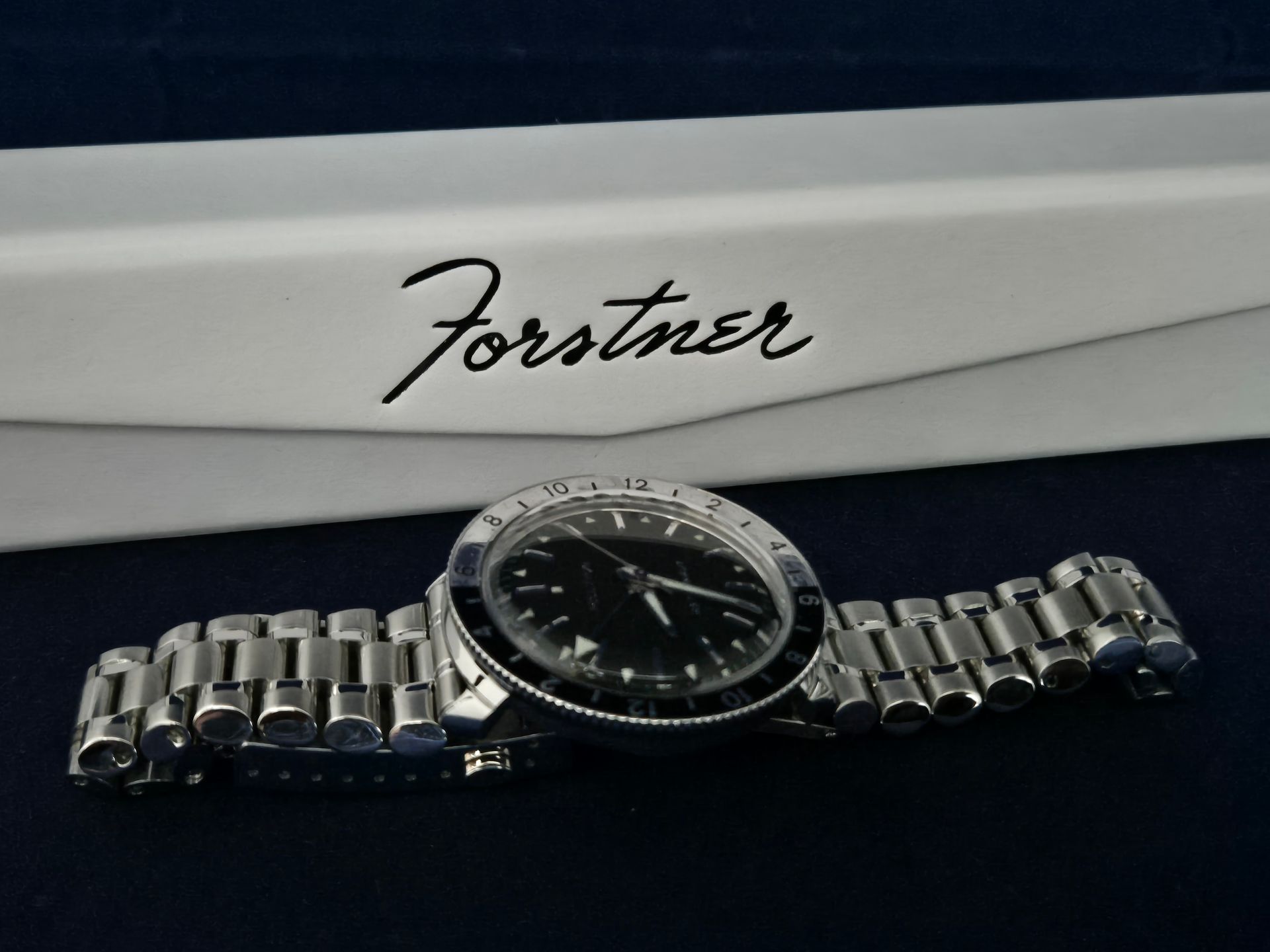 Forstner-branded wristwatch with metal bracelet on a dark surface in a presentation box